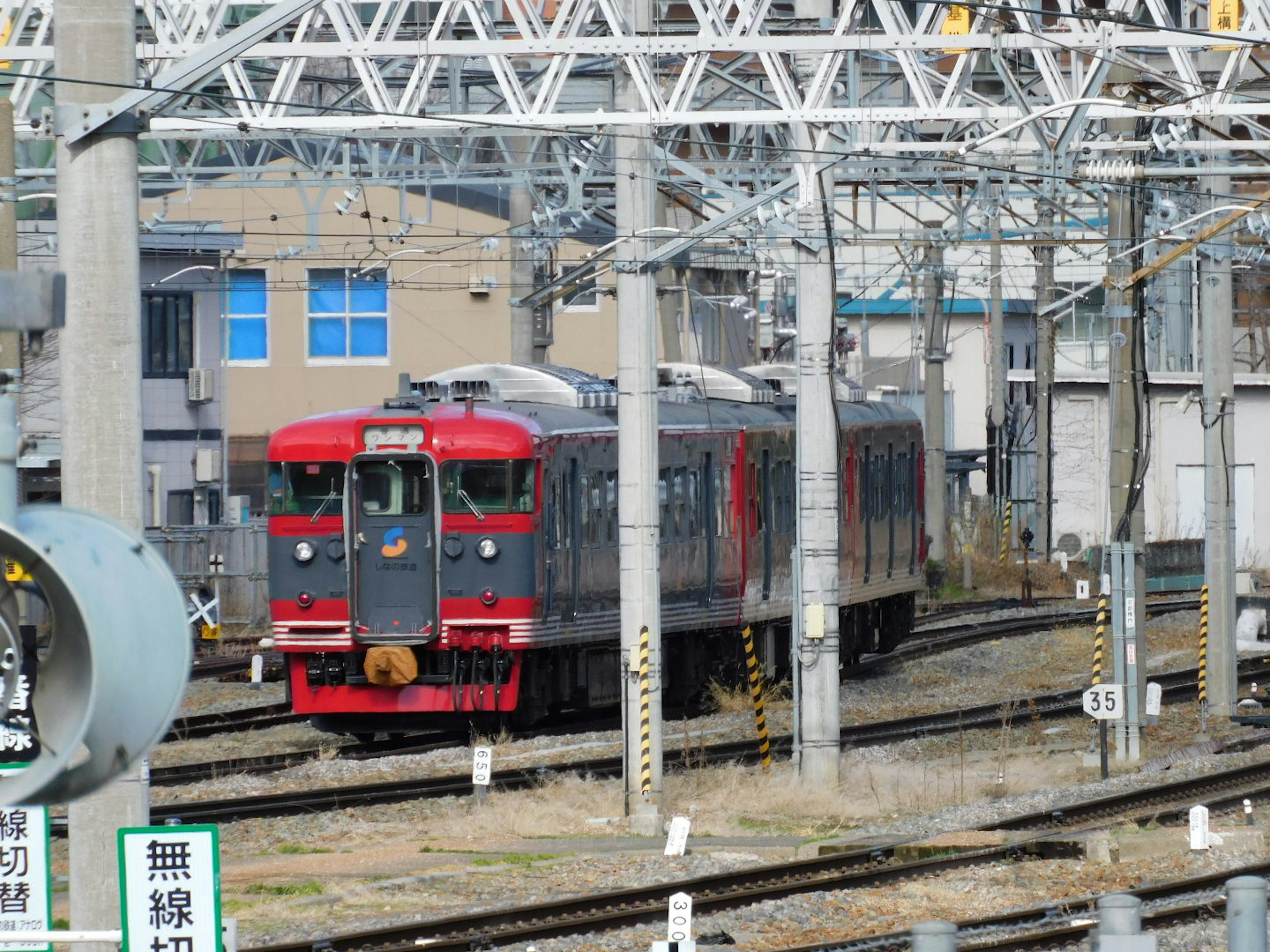 Red train parked on tracks near buildings