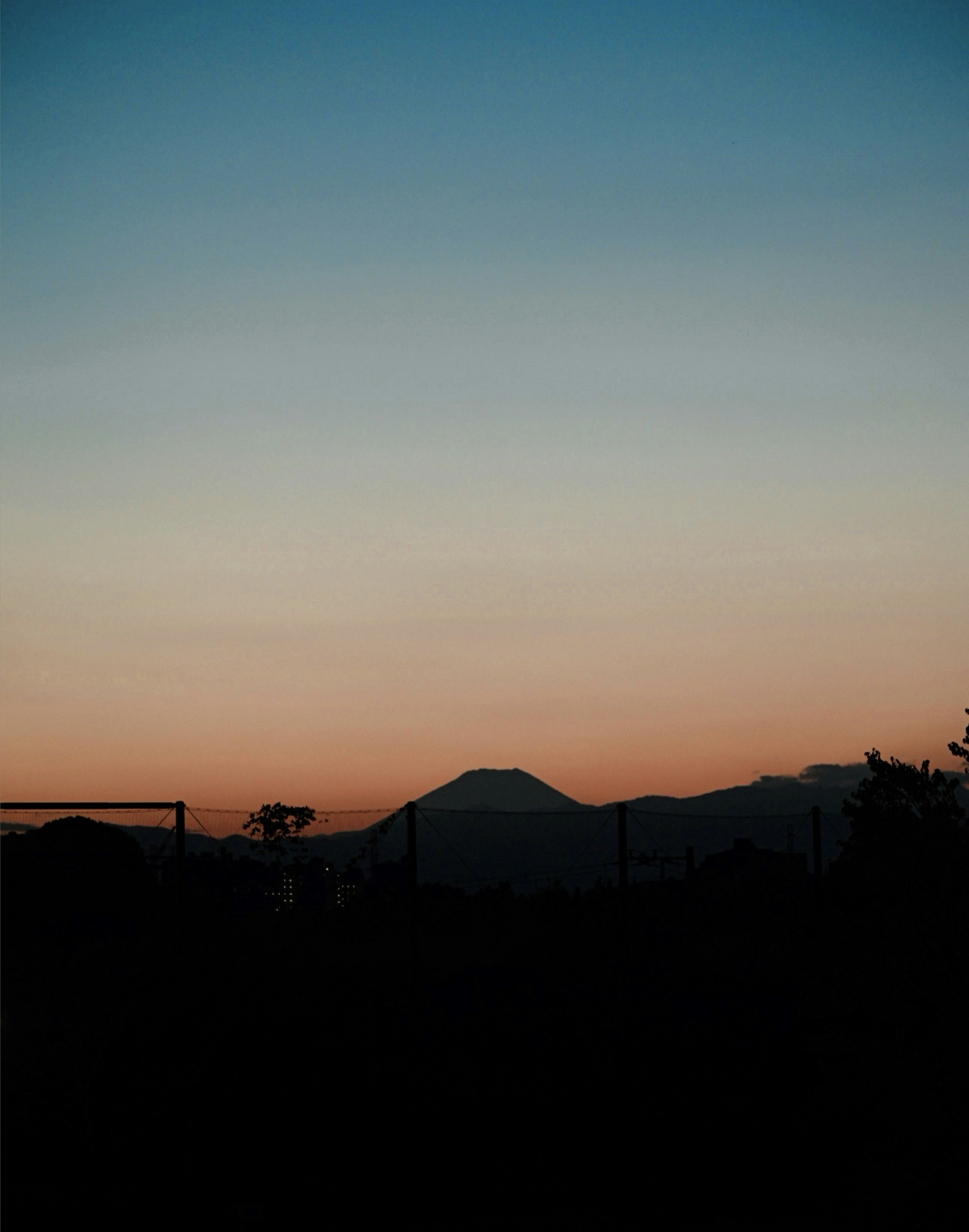 夕焼けに染まる山々のシルエットと青い空