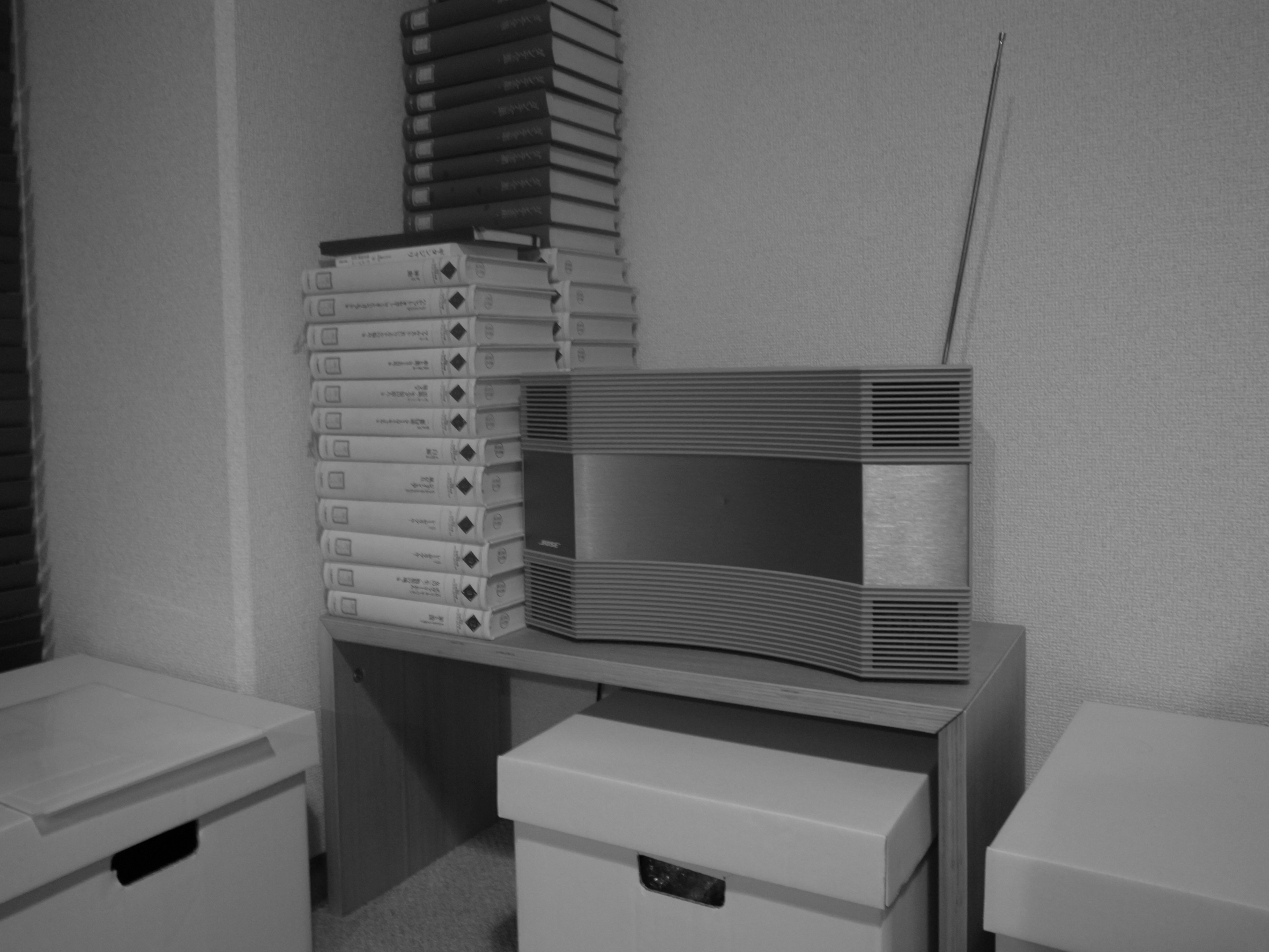 A monochrome room featuring a radio next to white storage boxes stacked with cassette tapes