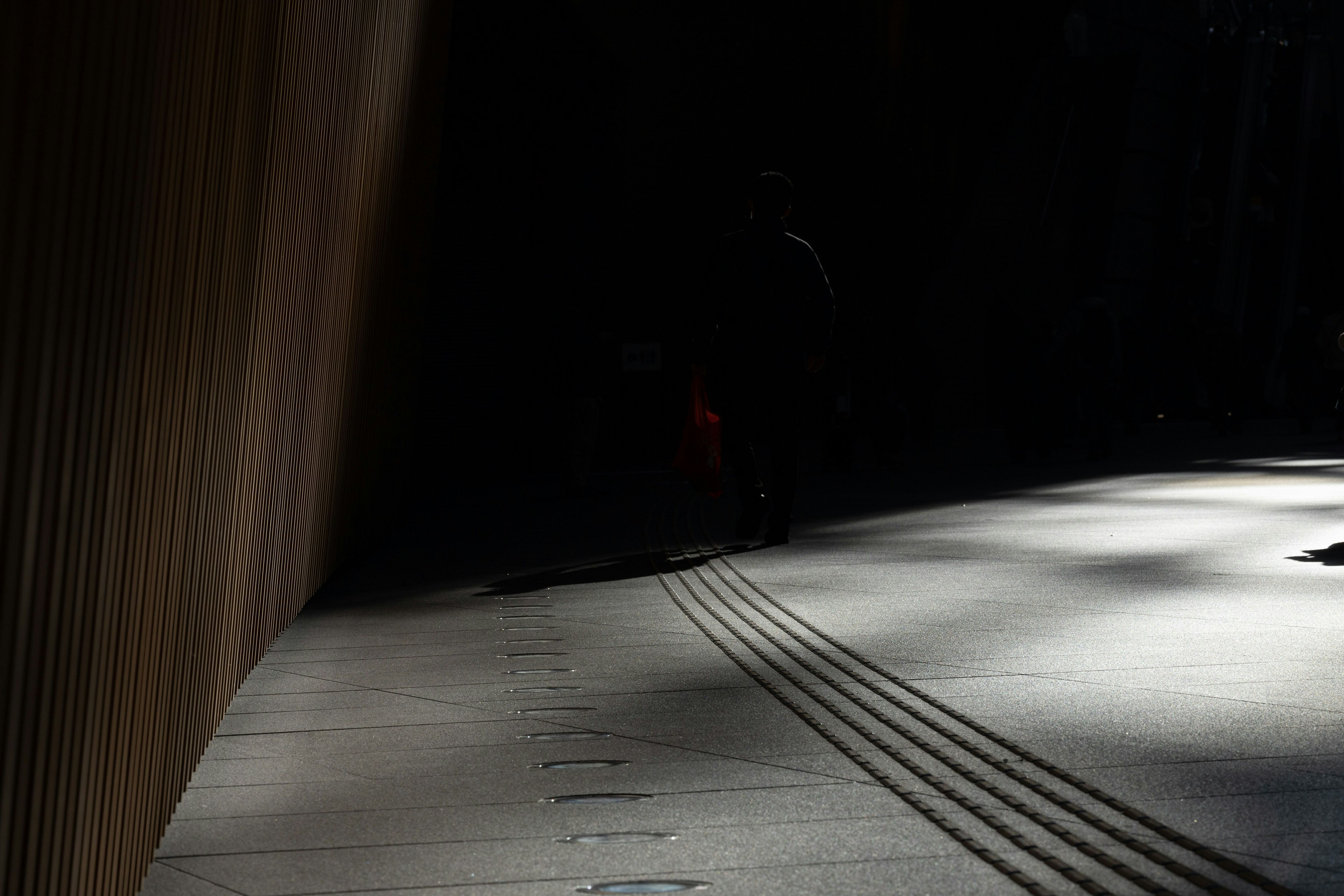 Una sección de un camino con luz brillando a través de un fondo oscuro y sombras