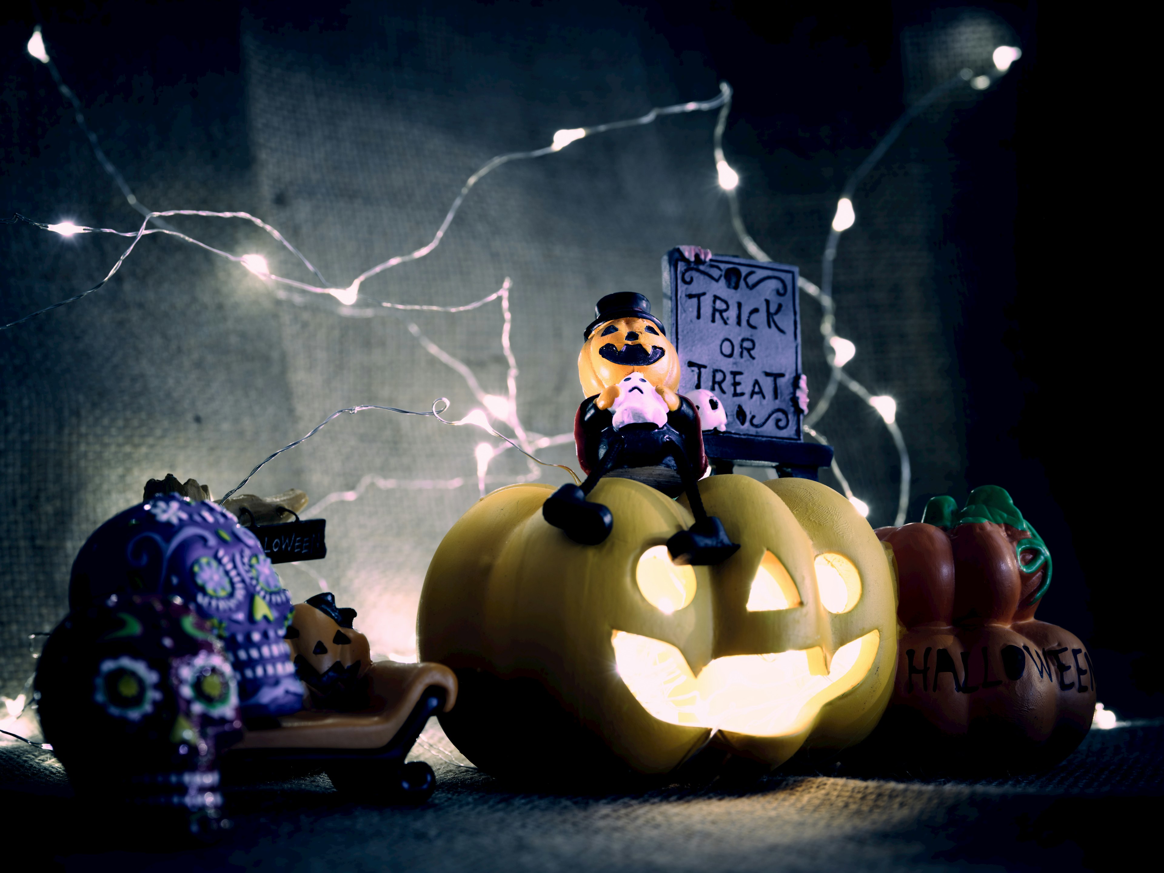 Cảnh vật theo chủ đề Halloween với một quả bí ngô phát sáng và trang trí một bức tượng nhỏ ngồi trên quả bí ngô được bao quanh bởi những quả bí ngô nhỏ hơn và đồ trang trí