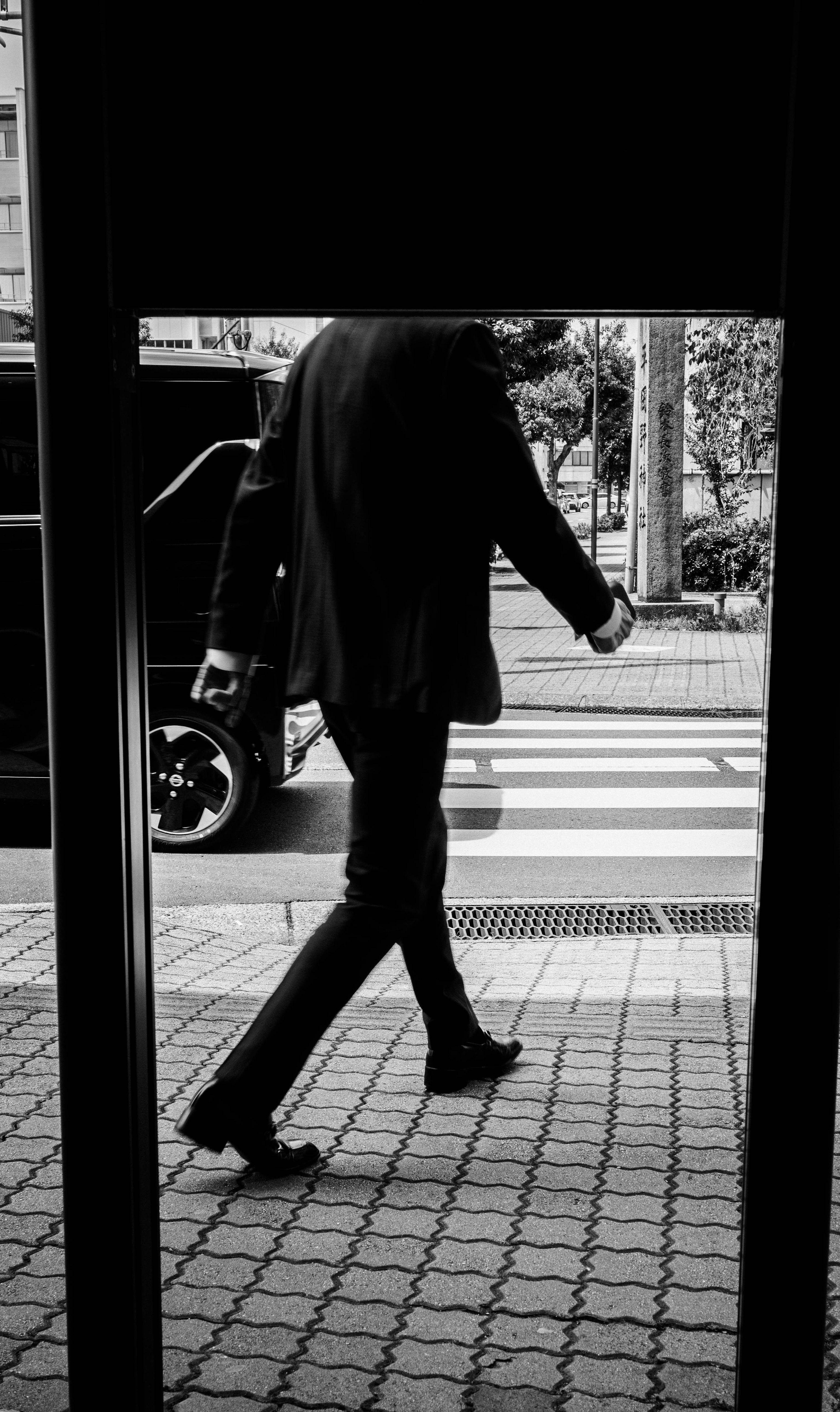 A man in a black suit walking captured from a doorway