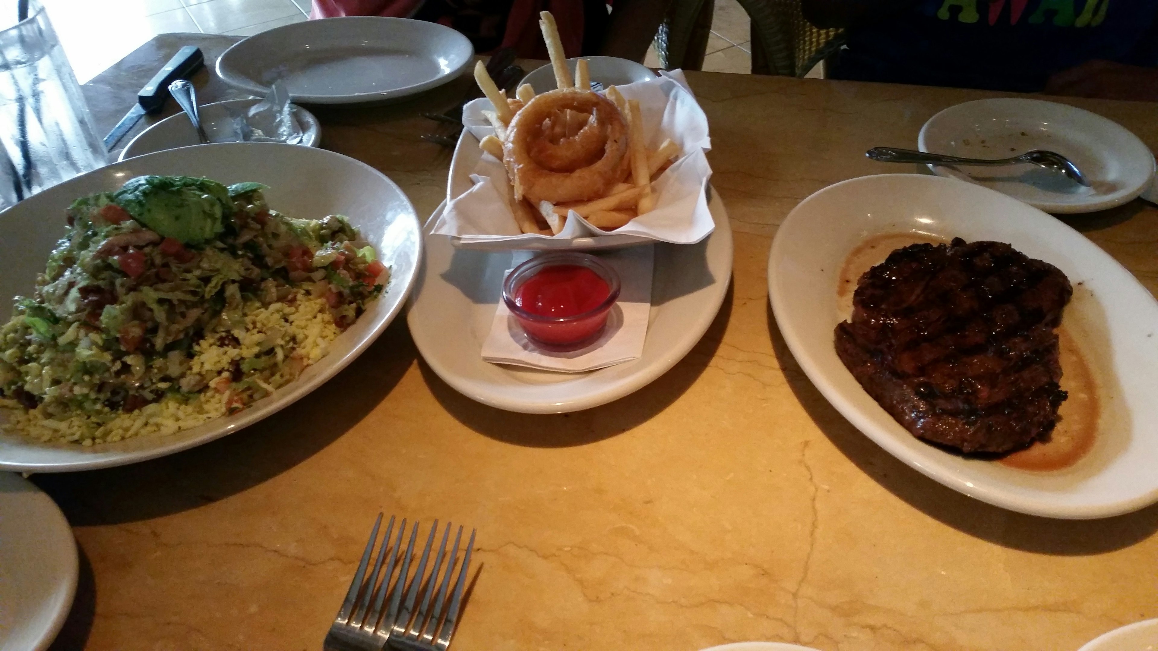 A delicious spread of food featuring salad, onion rings, and grilled meat