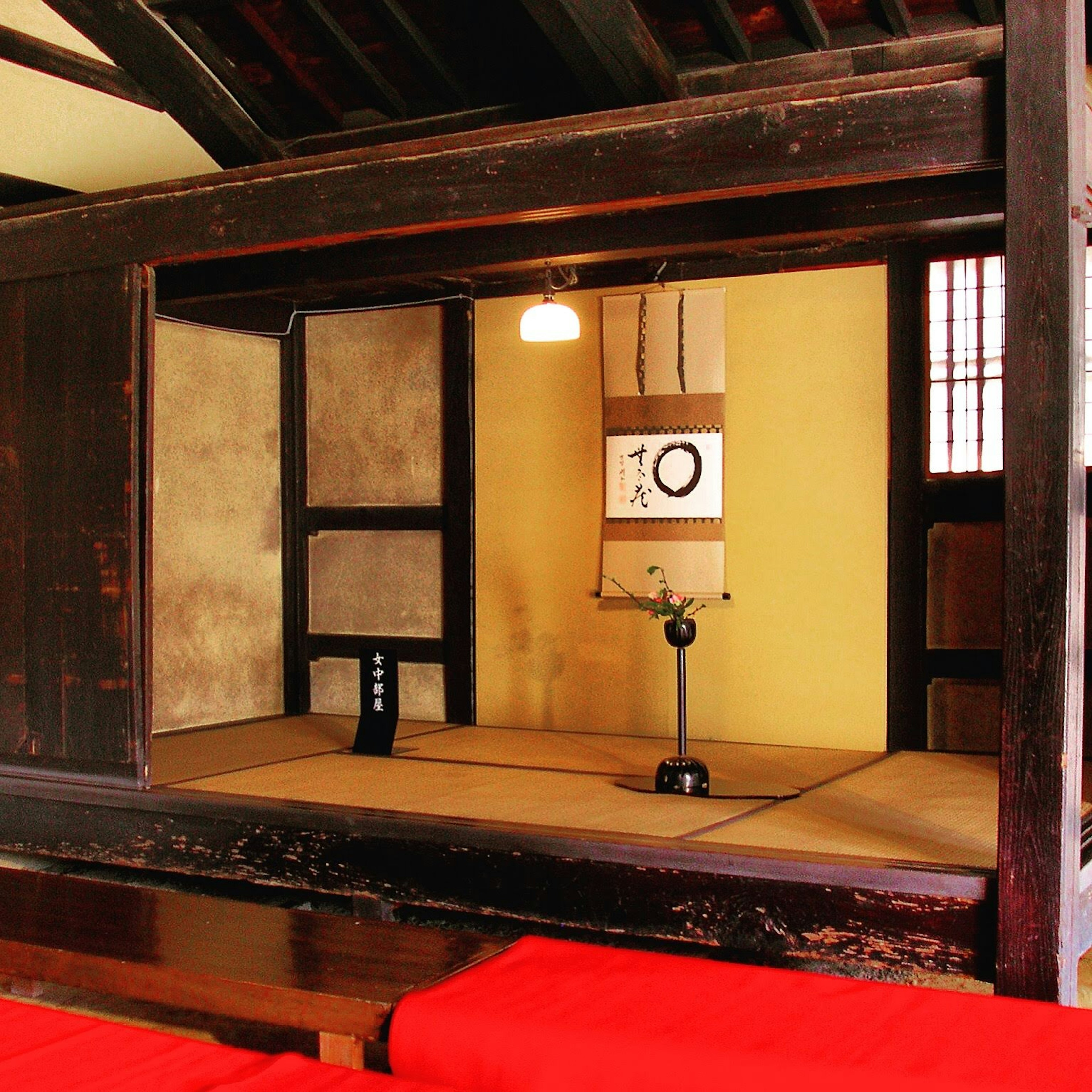 View through a window into a traditional Japanese room featuring tatami mats and unique lighting