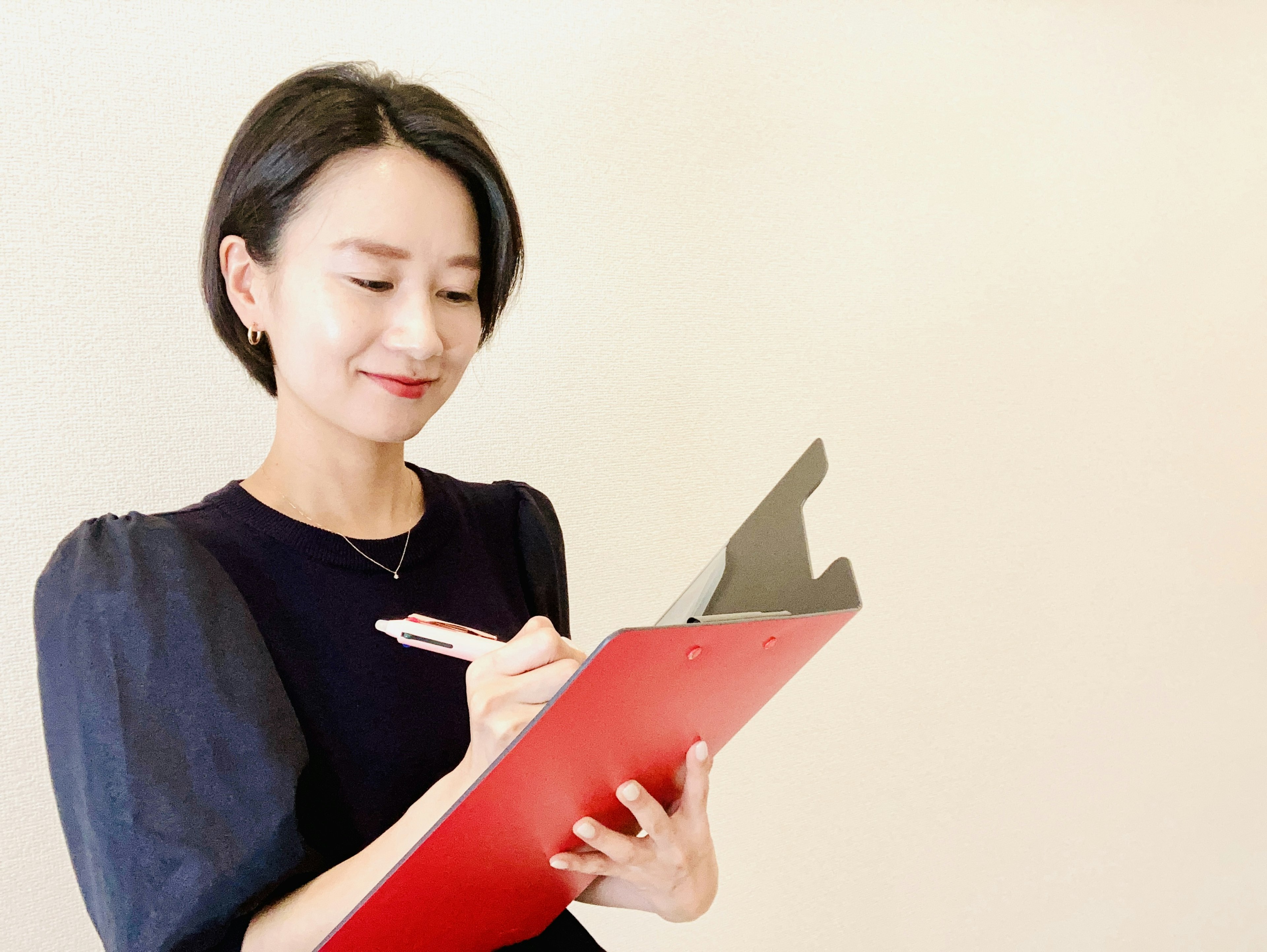 Una mujer escribiendo en un clipboard rojo