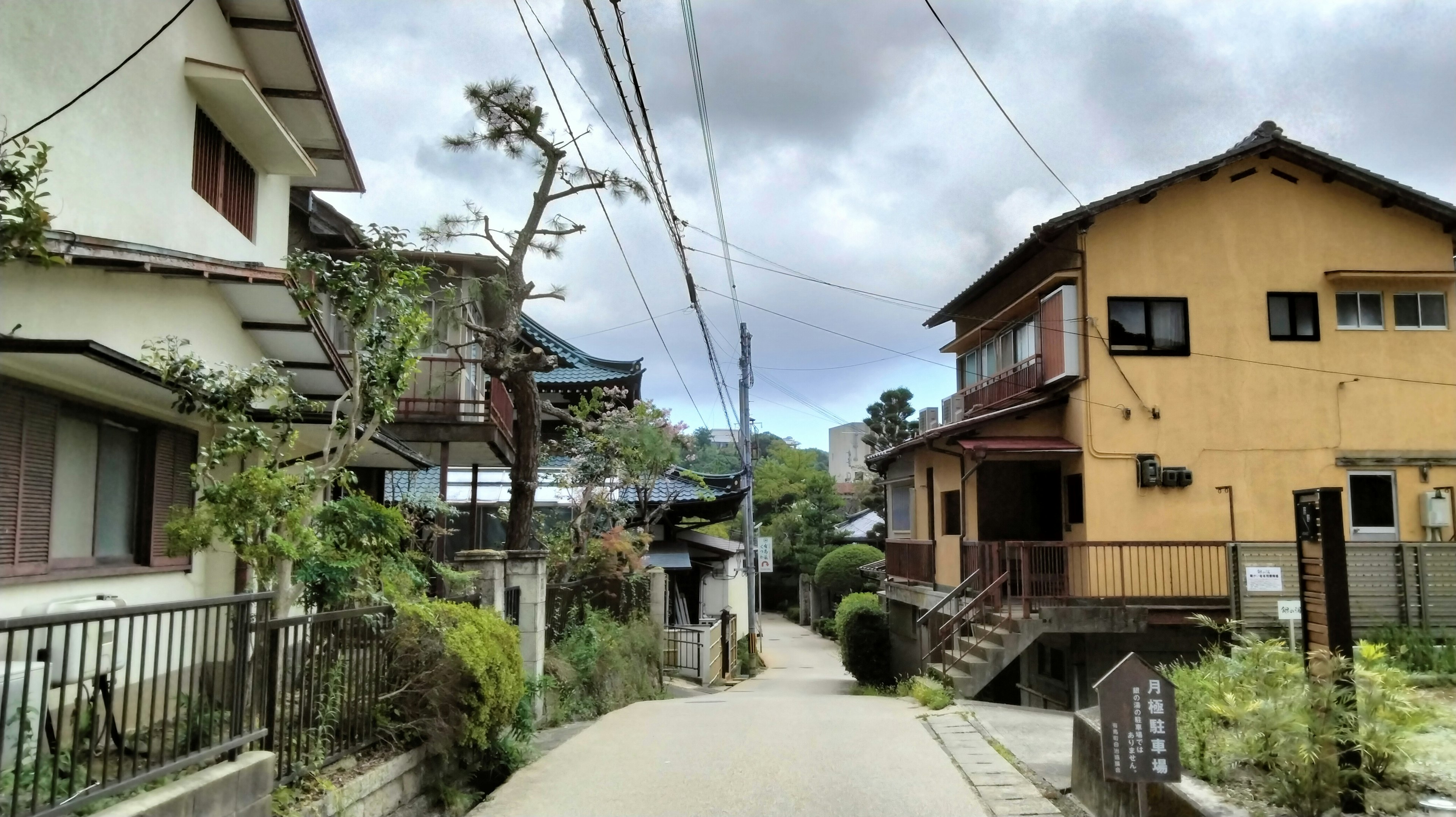 Calle estrecha flanqueada por casas y cielo nublado