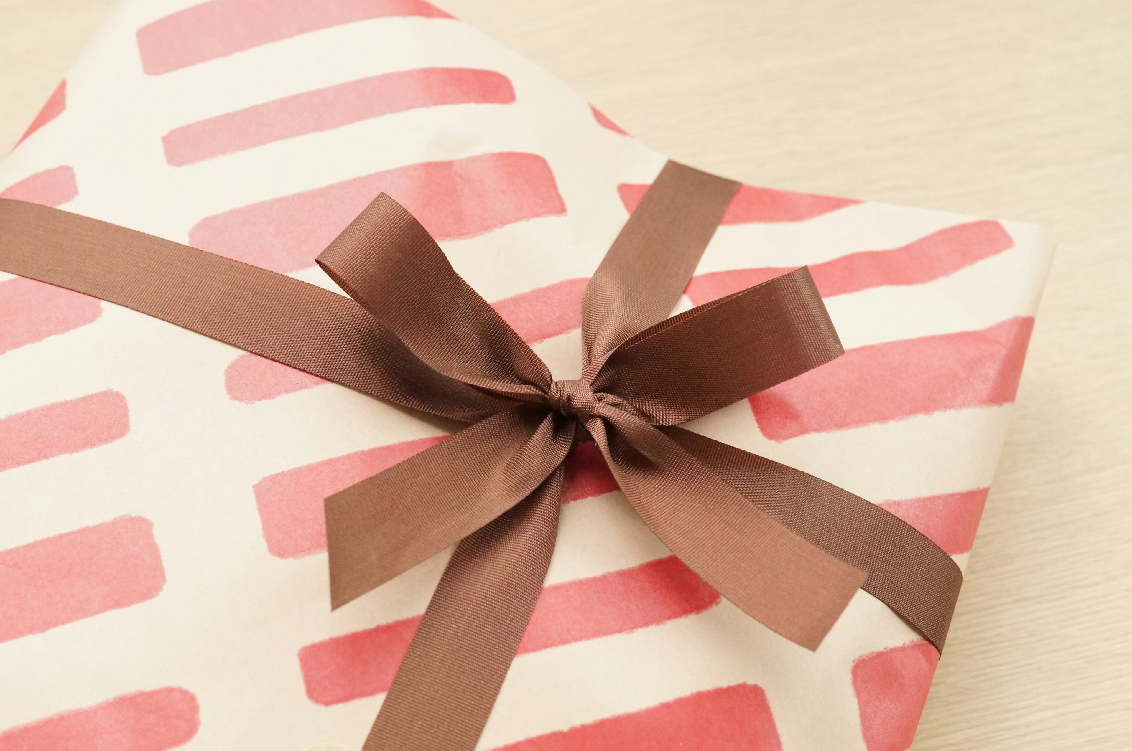 A gift wrapped in red striped paper with a brown ribbon tied neatly