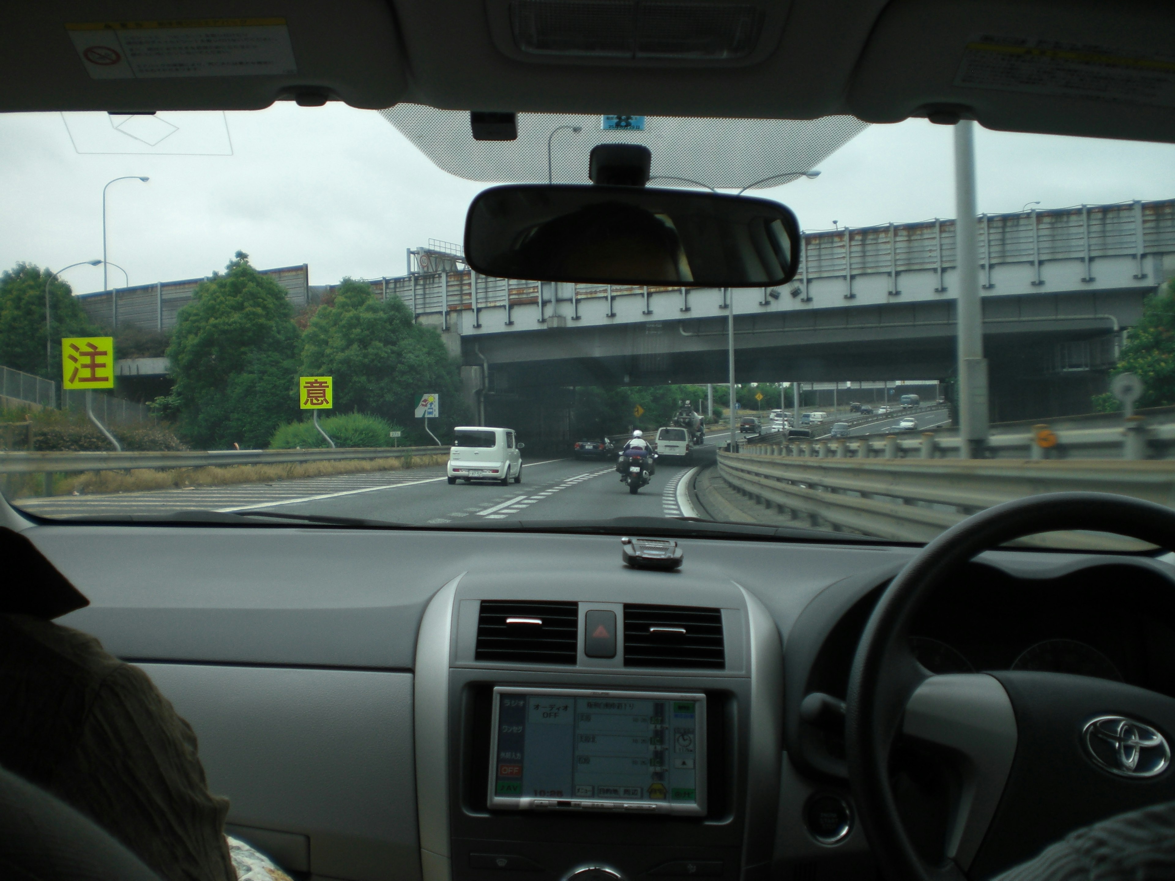 Vista di un'autostrada dall'interno di un'auto cruscotto visibile con la mano del conducente