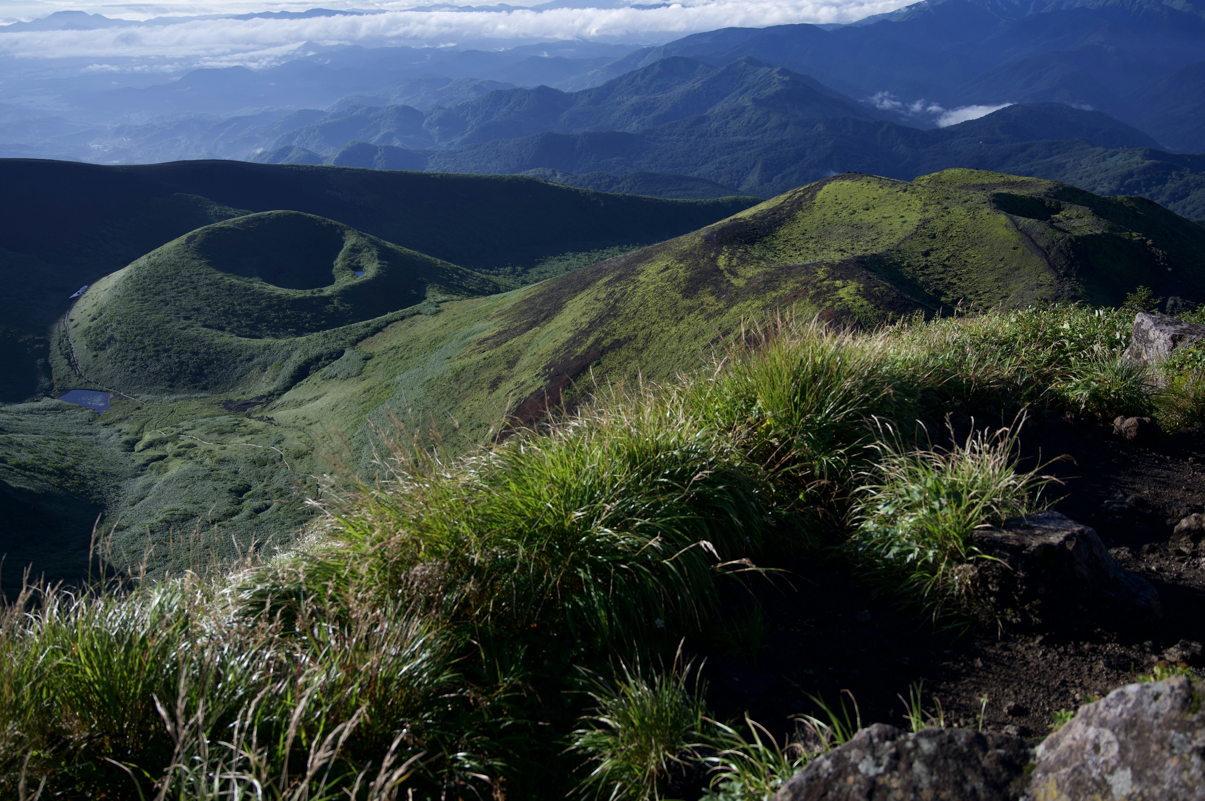 เนินเขาสีเขียวสดและภูเขาใต้ท้องฟ้าที่ปลอดโปร่ง