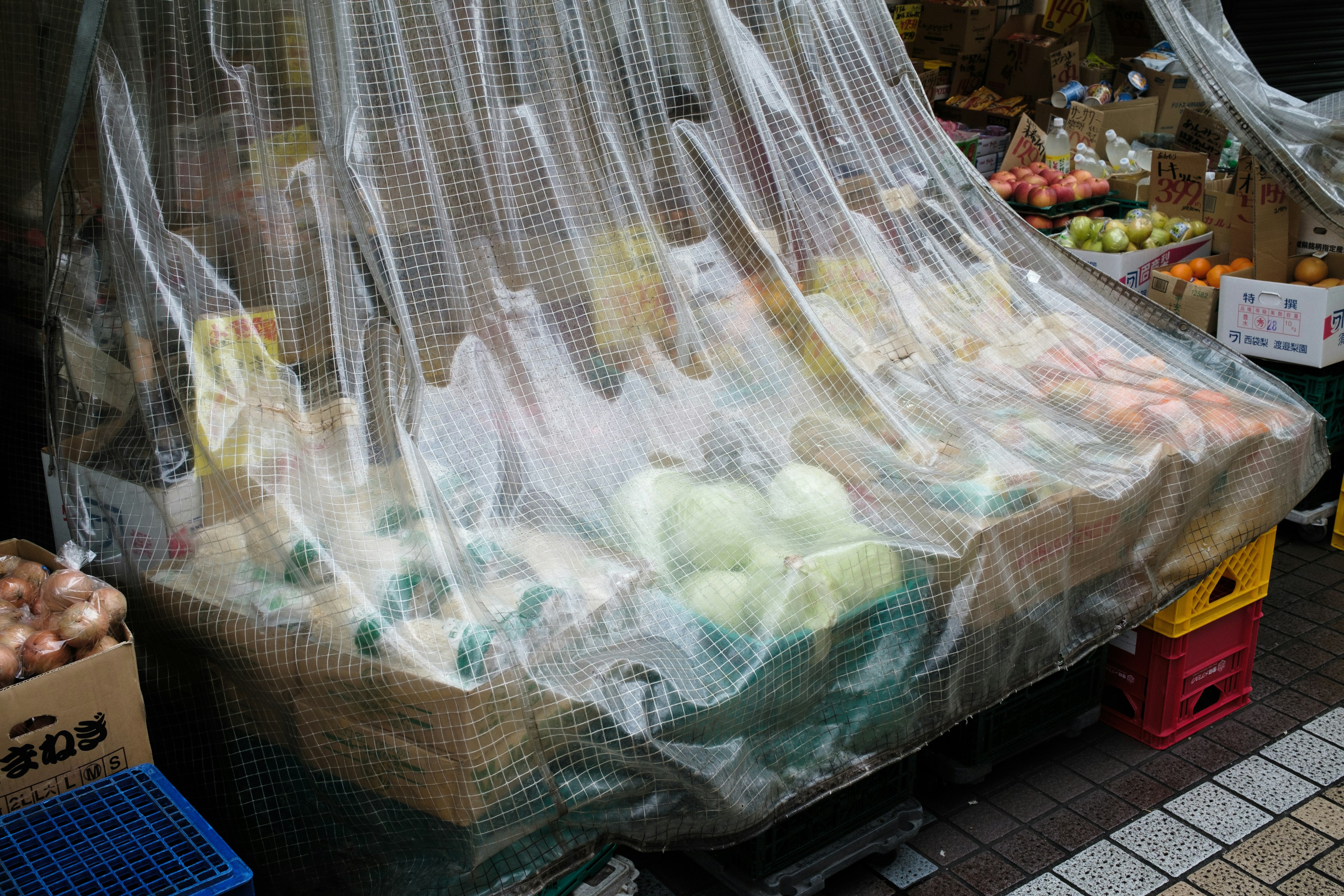 Vegetables covered with clear plastic at a market stall