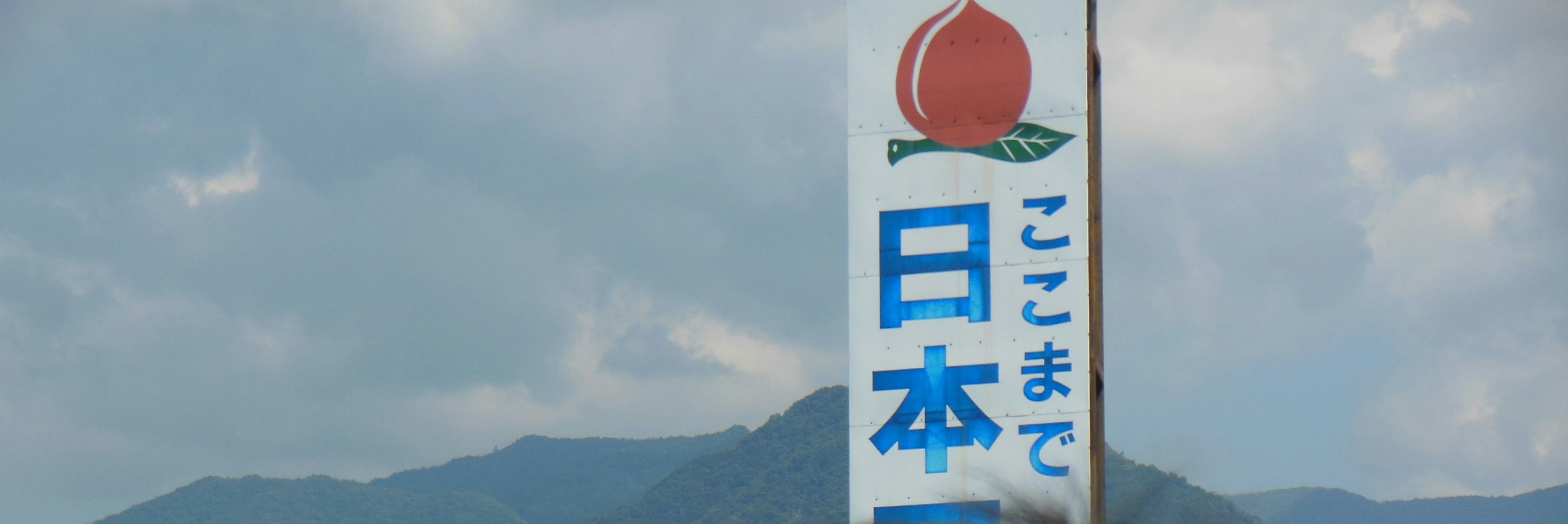 Schild, das Japan mit einem Pfirsichsymbol unter einem blauen Himmel anzeigt