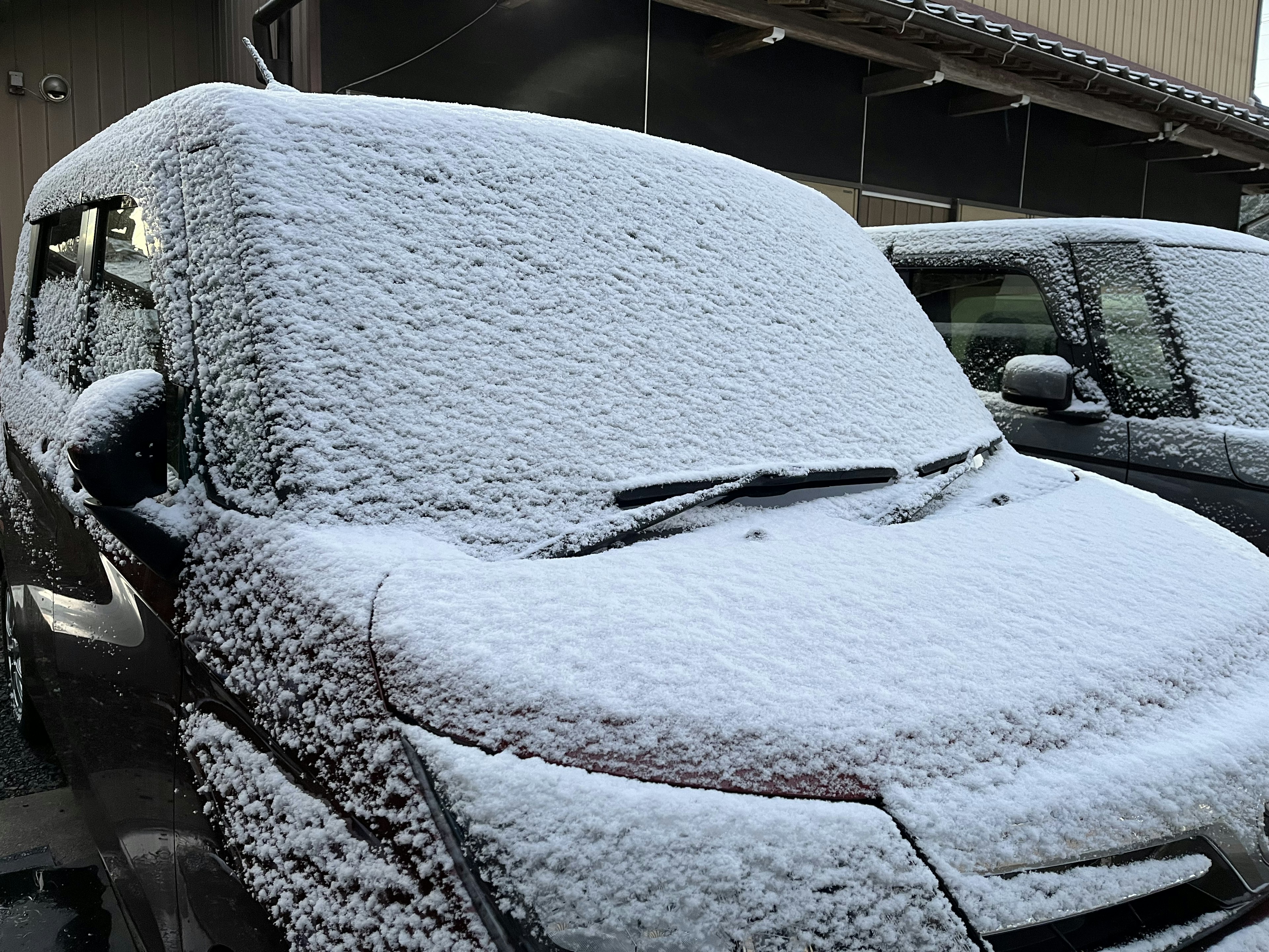 Auto coperta di neve con il cofano e il parabrezza innevati