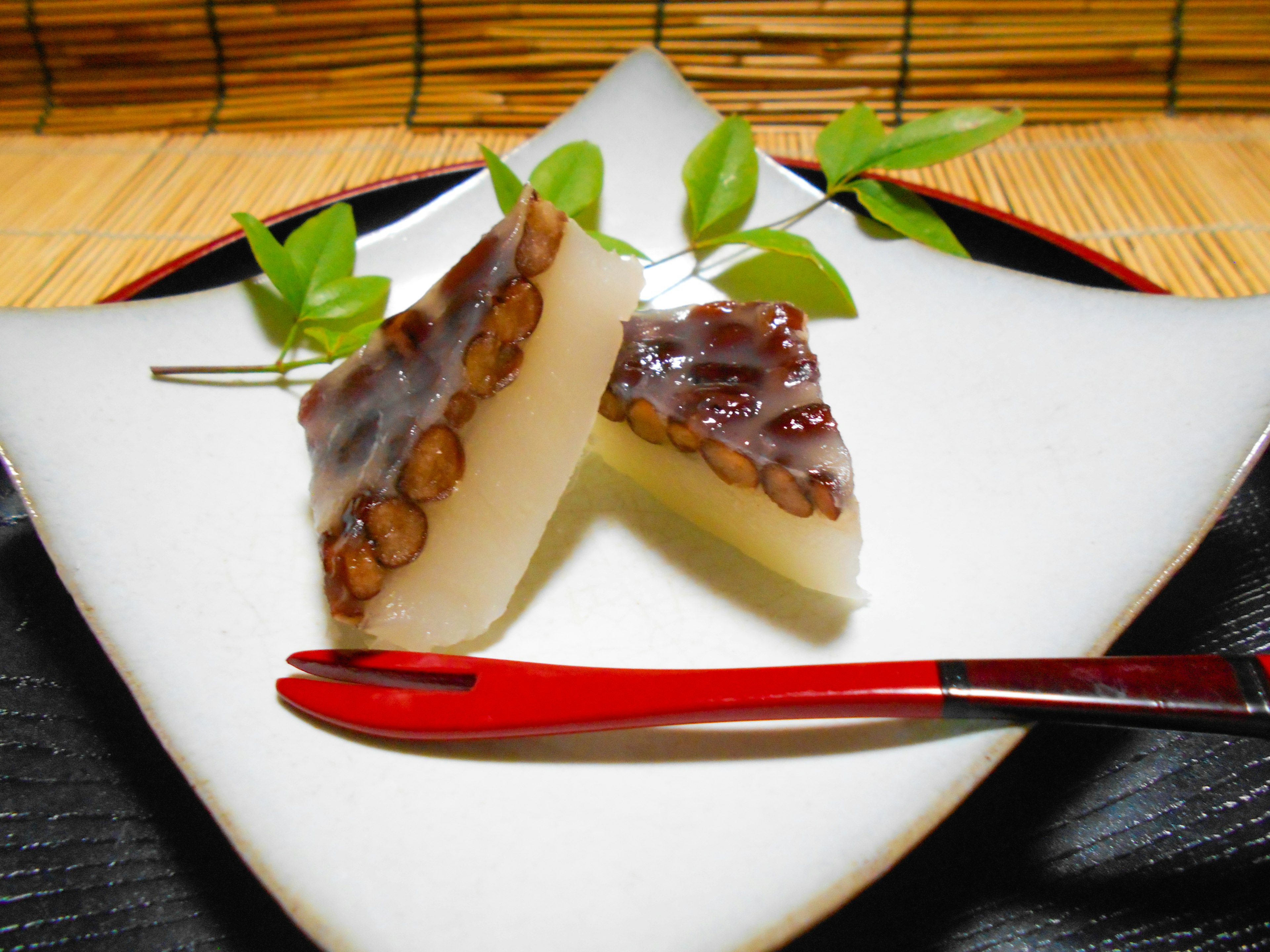 Douceurs japonaises appelées yokan présentées sur une assiette blanche avec des feuilles vertes