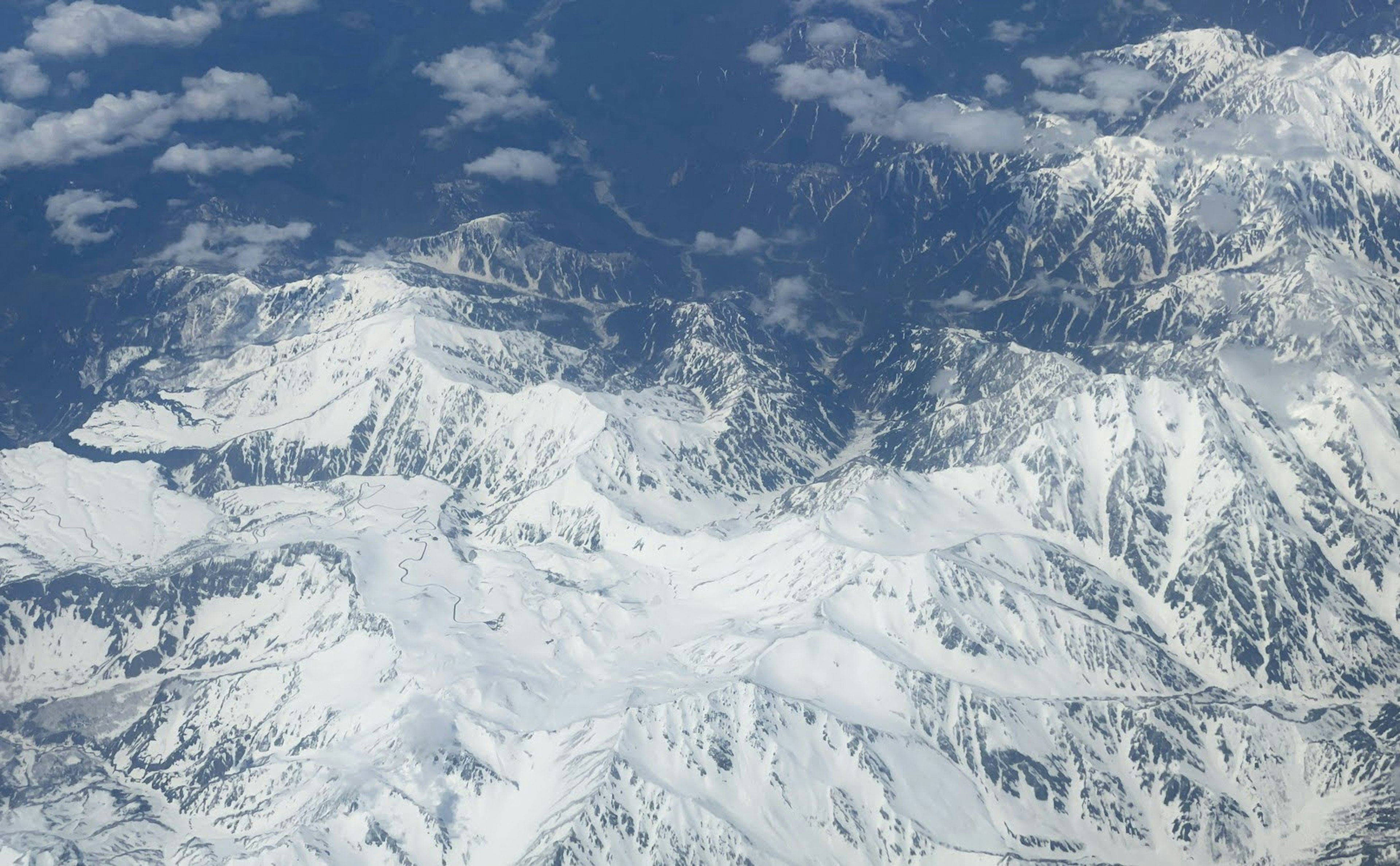 Vista aerea di una catena montuosa innevata e cielo blu