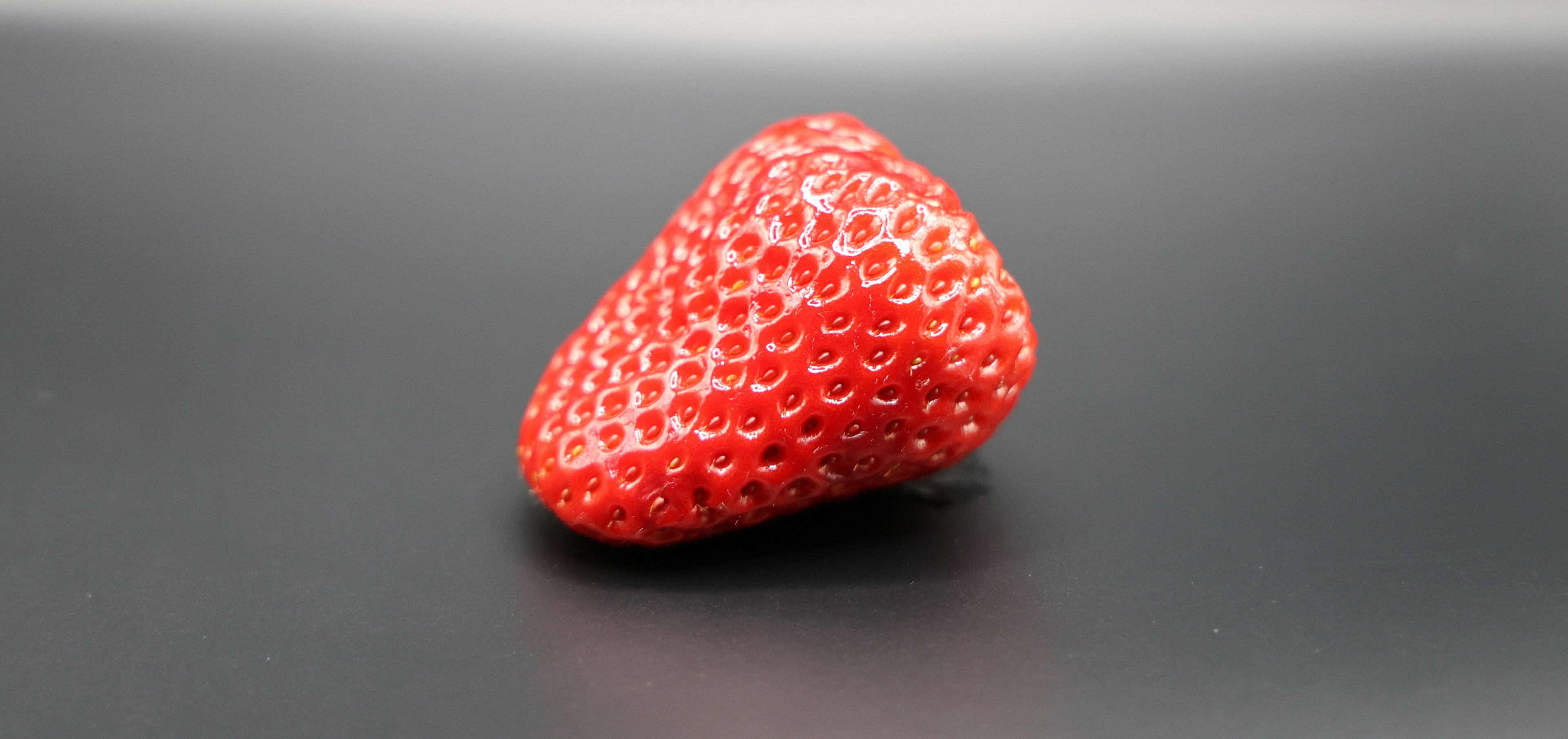 A vibrant red strawberry placed on a black background