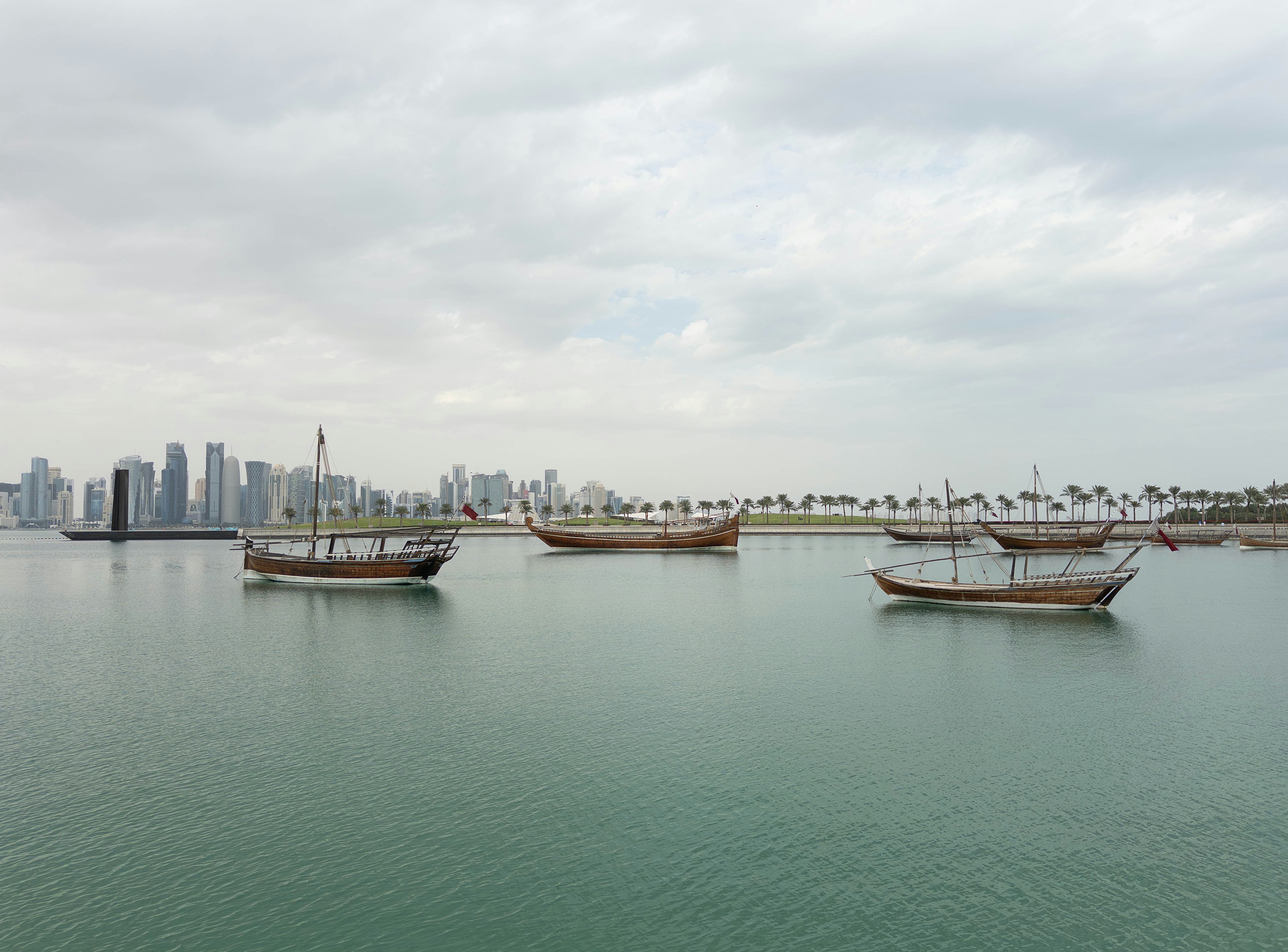 Traditionelle Boote, die auf dem Wasser schwimmen, mit einer modernen Stadtansicht im Hintergrund