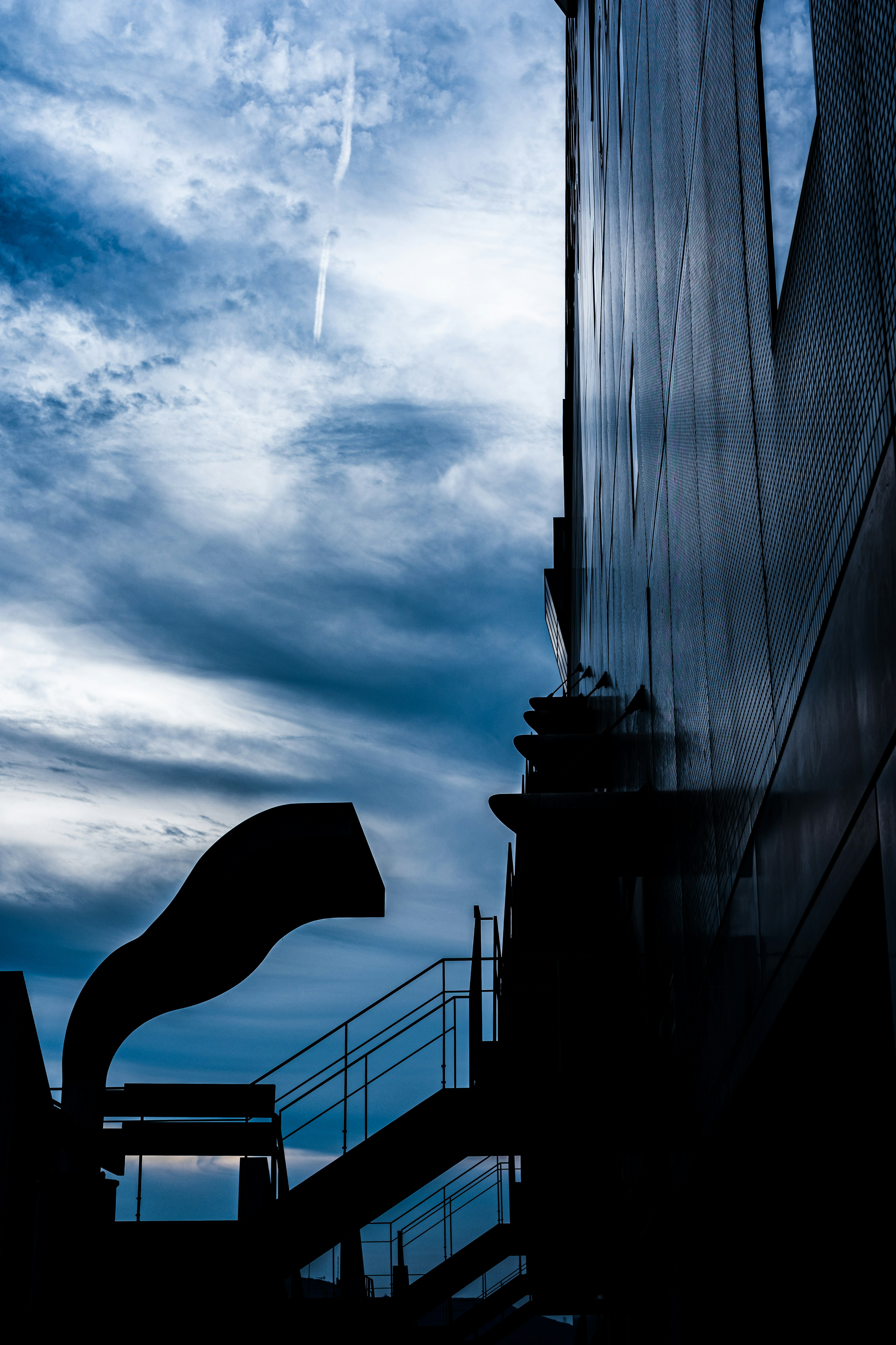 Silhouette d'un bâtiment avec un ciel bleu et des nuages en arrière-plan présentant des éléments architecturaux uniques