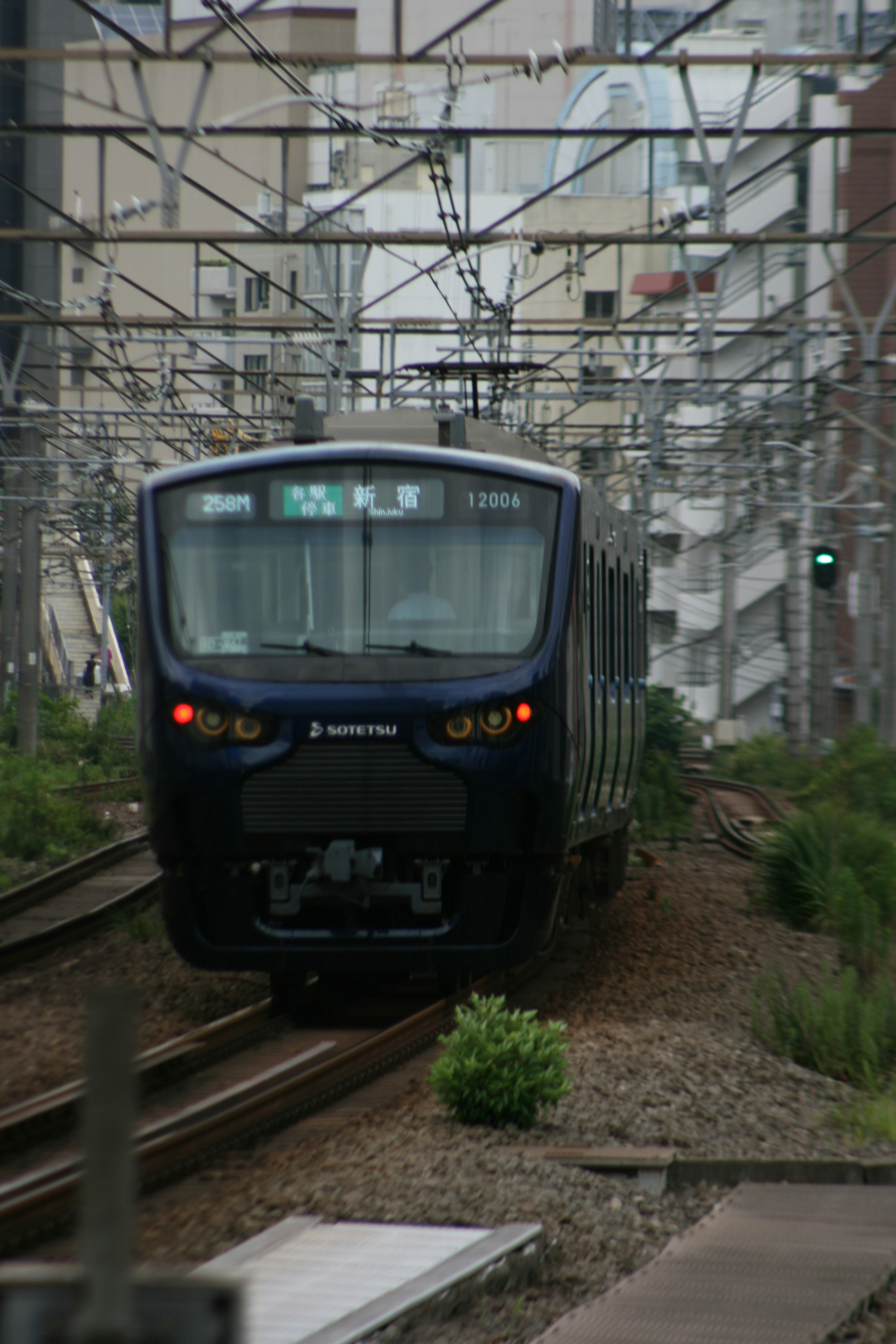 Blue train approaching on urban railway surrounded by buildings