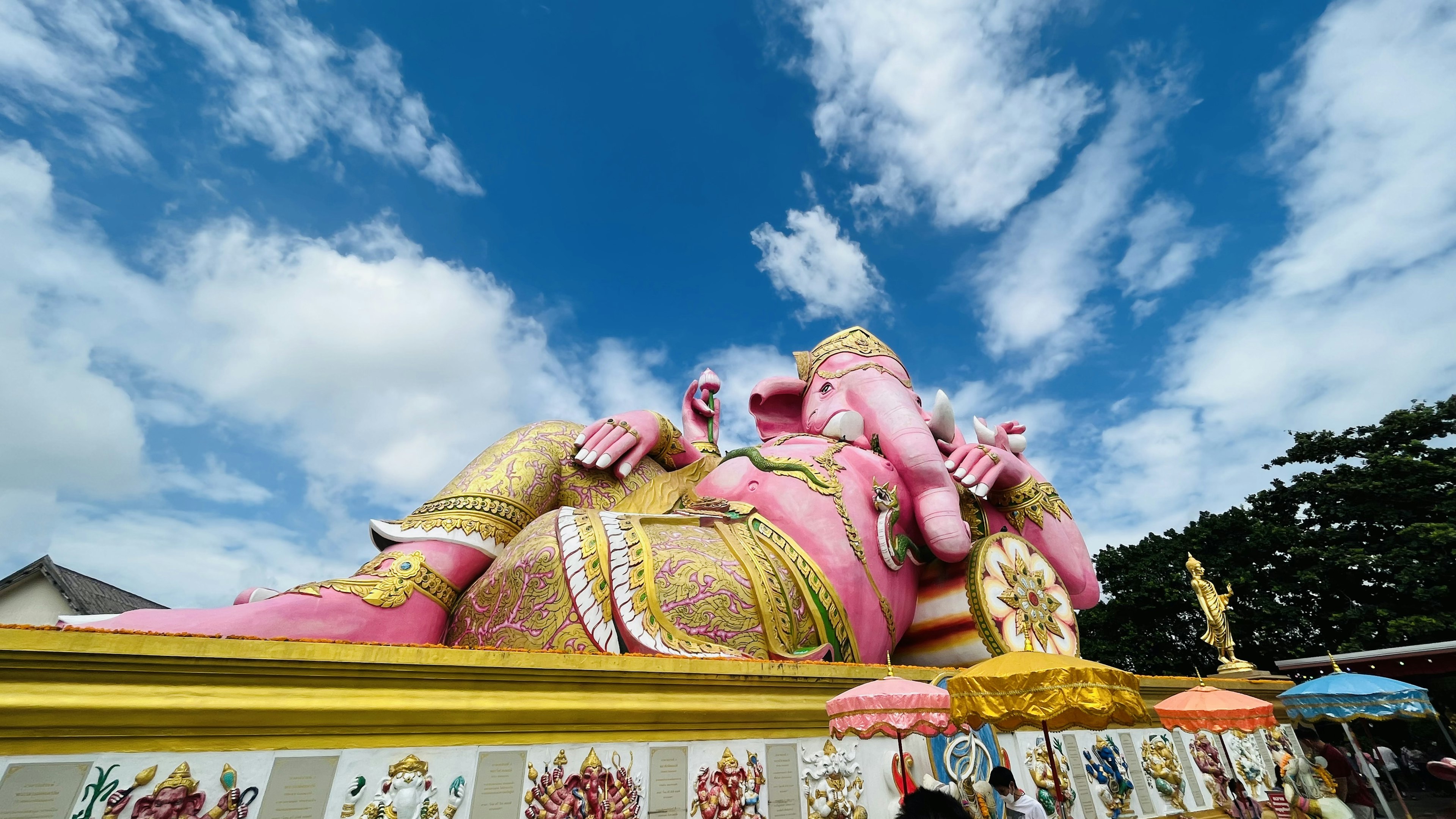 Grande statue de Ganesh rose allongée sous un ciel bleu