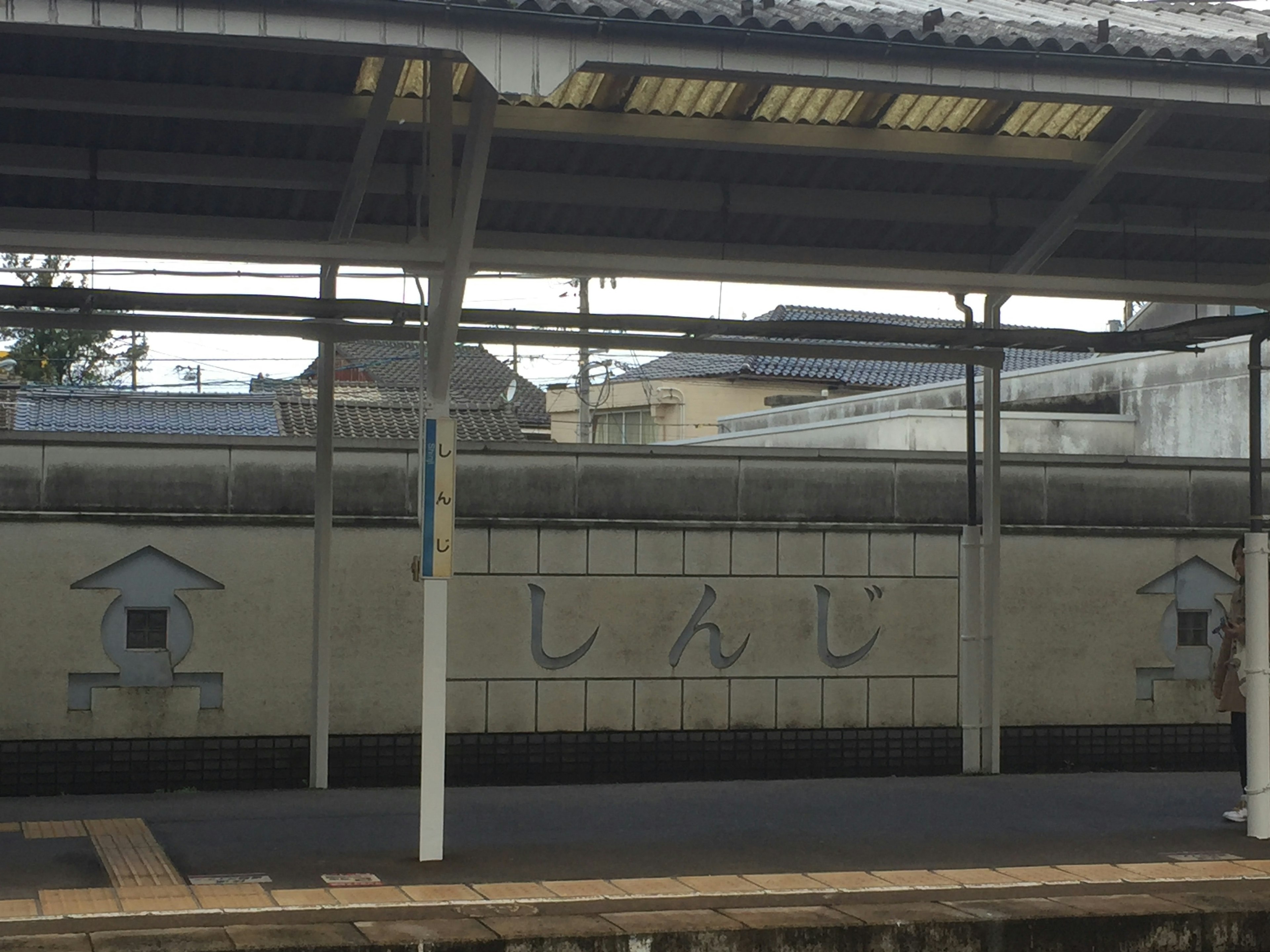 Insegna della piattaforma della stazione di Shinshi con tetto e pilastri di supporto