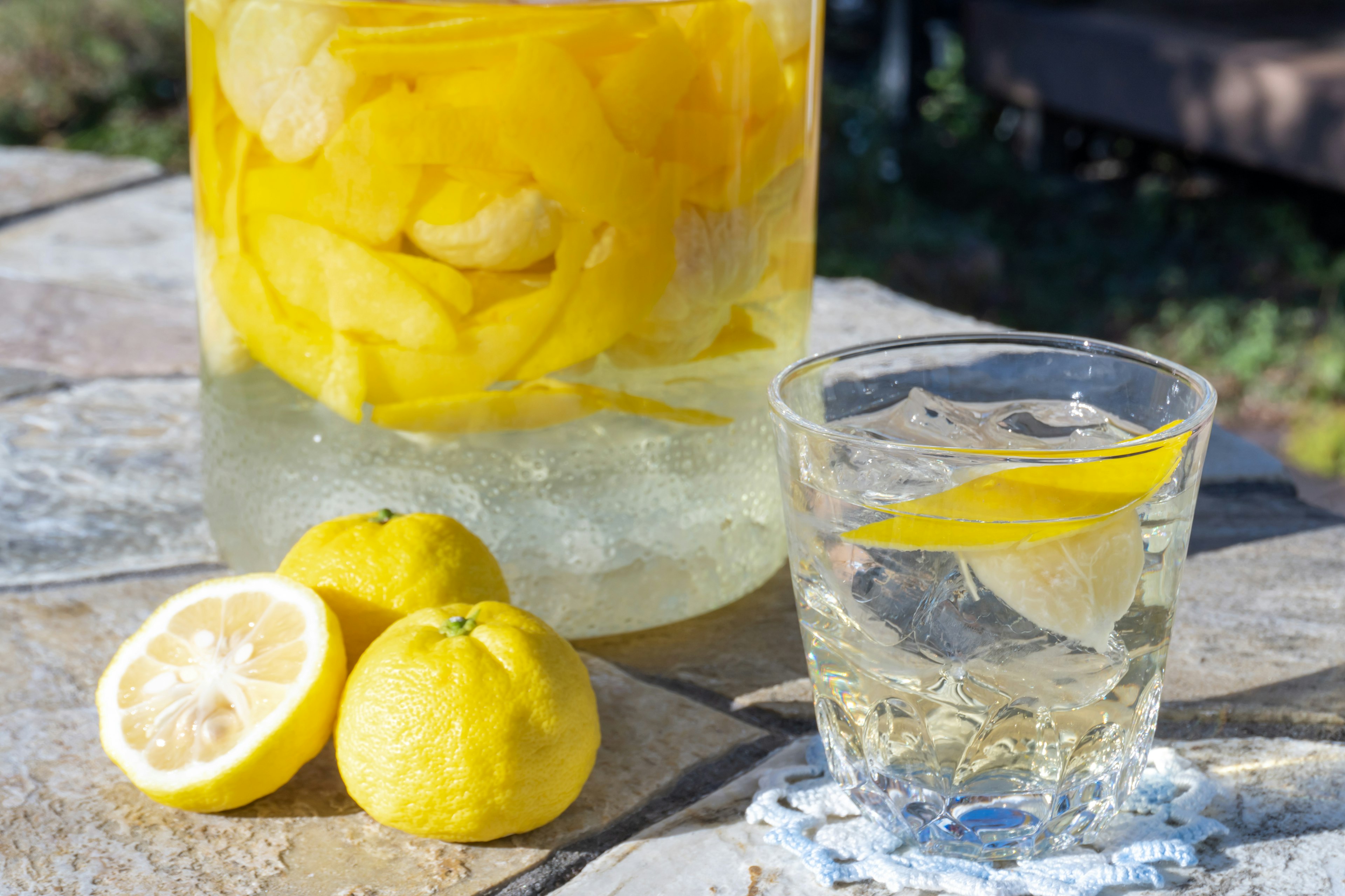 Ein erfrischendes Getränk mit schwimmenden Zitronenscheiben und ganzen Zitronen neben einem Glas