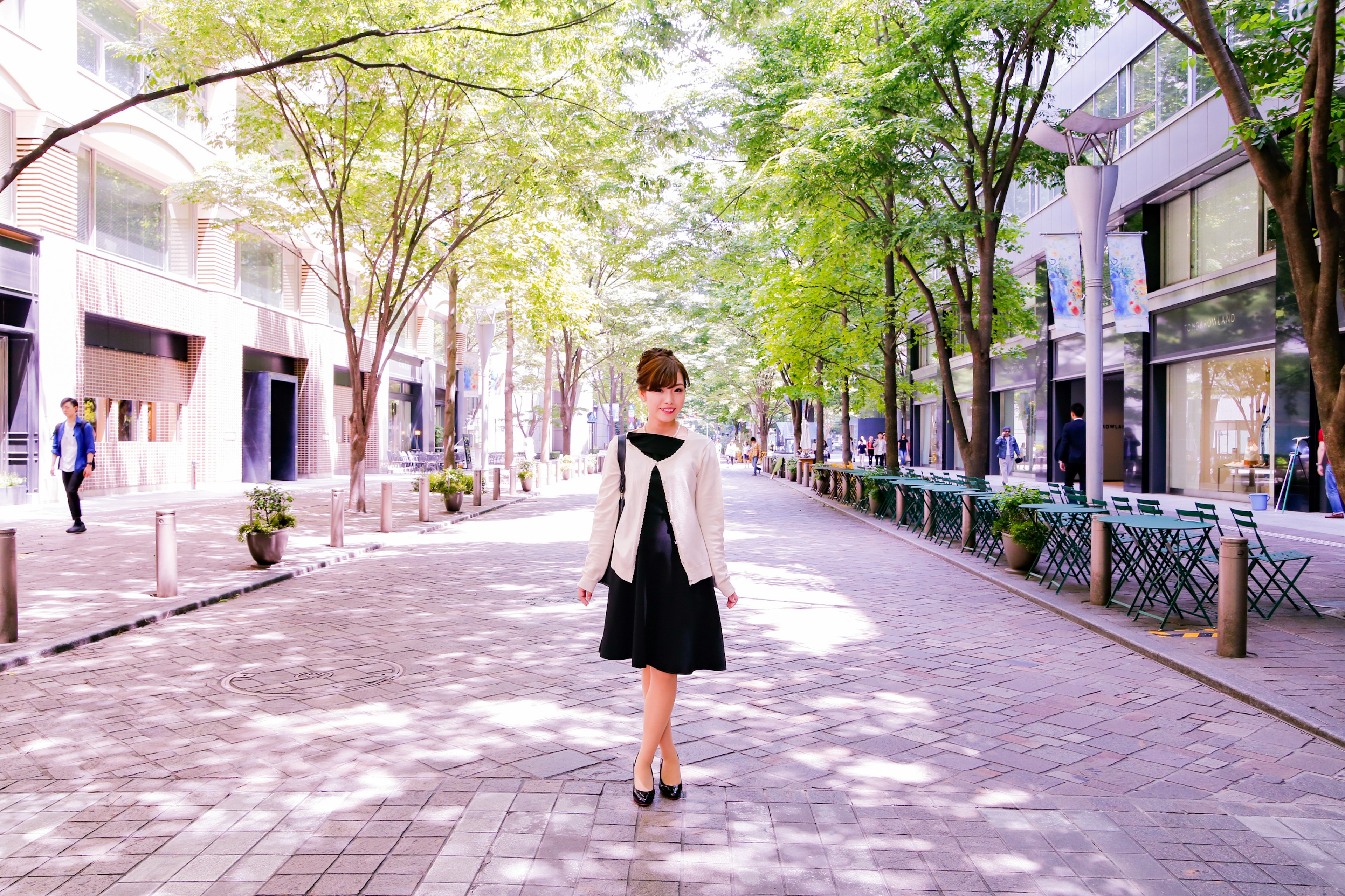 A woman walking on a tree-lined street in a black dress