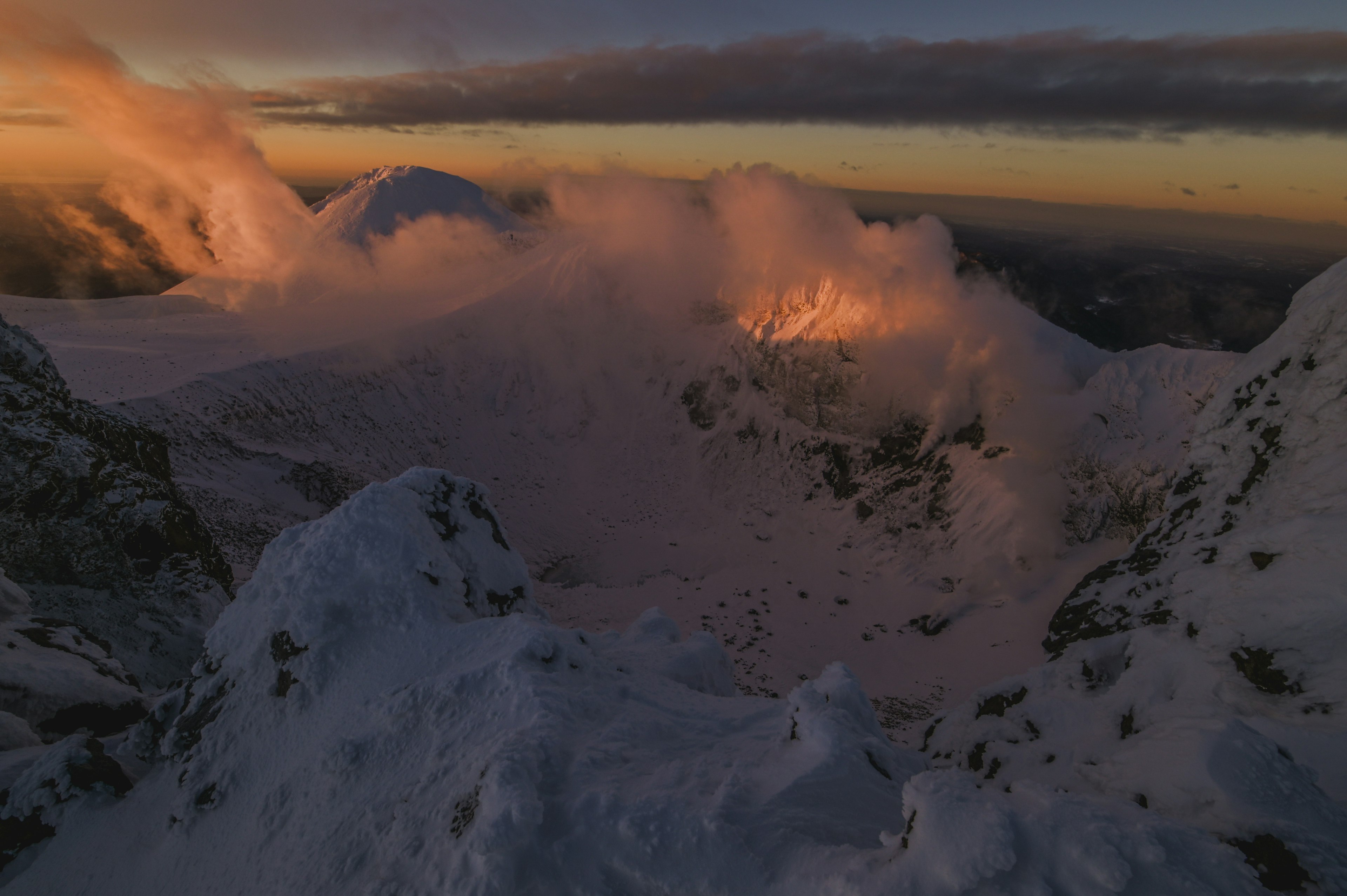 雪に覆われた山々が夕焼けに照らされる美しい景色