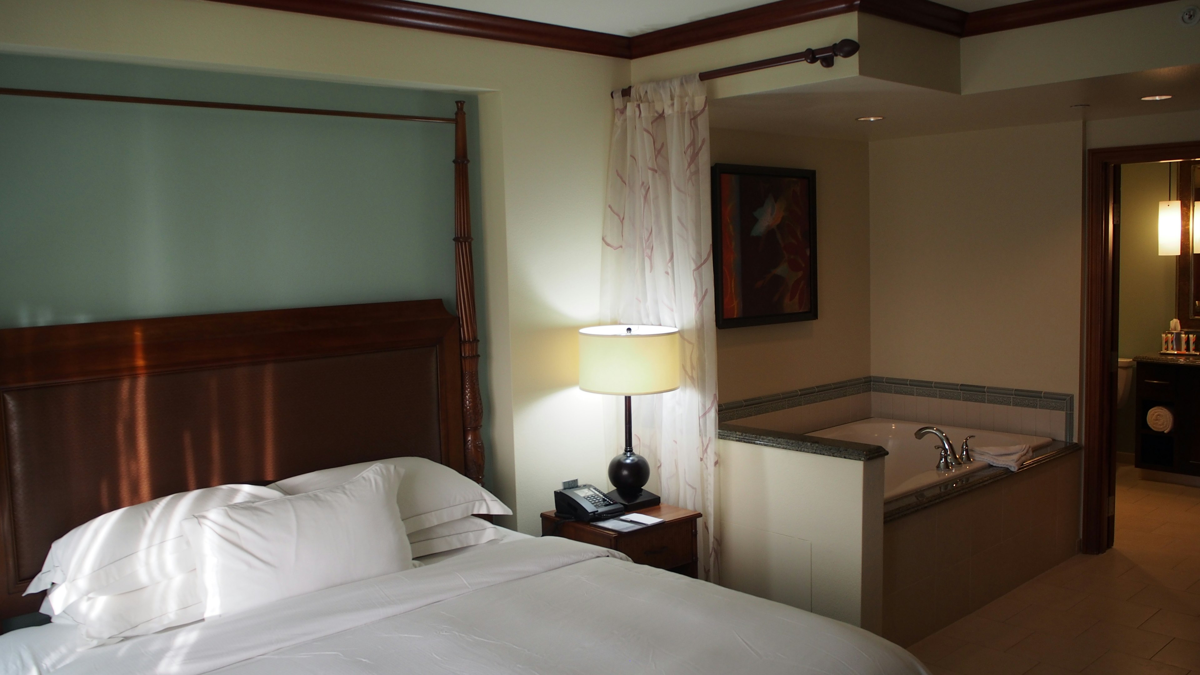 Luxury hotel room featuring a large bed and adjacent jacuzzi in the bathroom