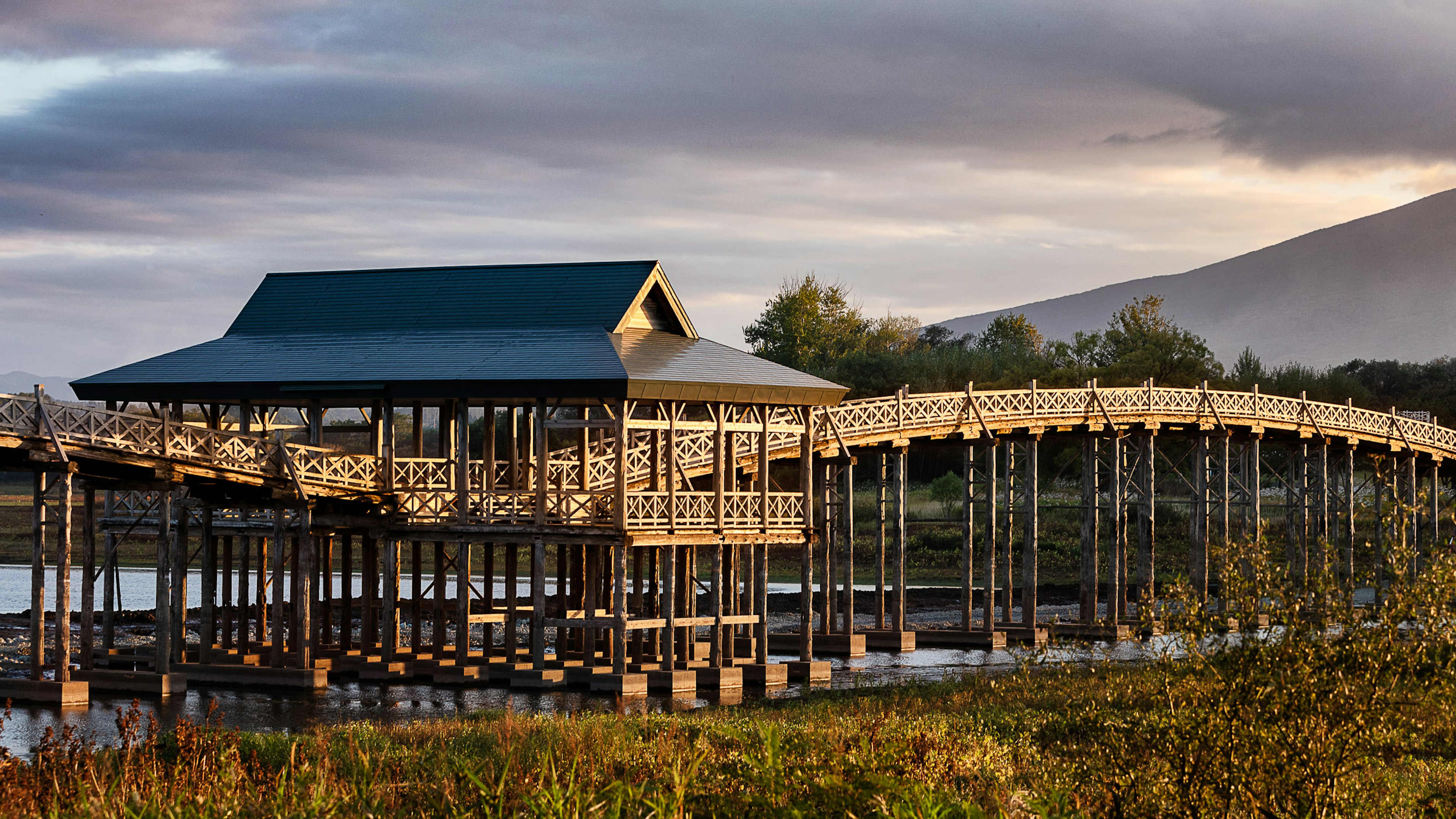 Wooden bridge and cabin on a calm lake surrounded by nature