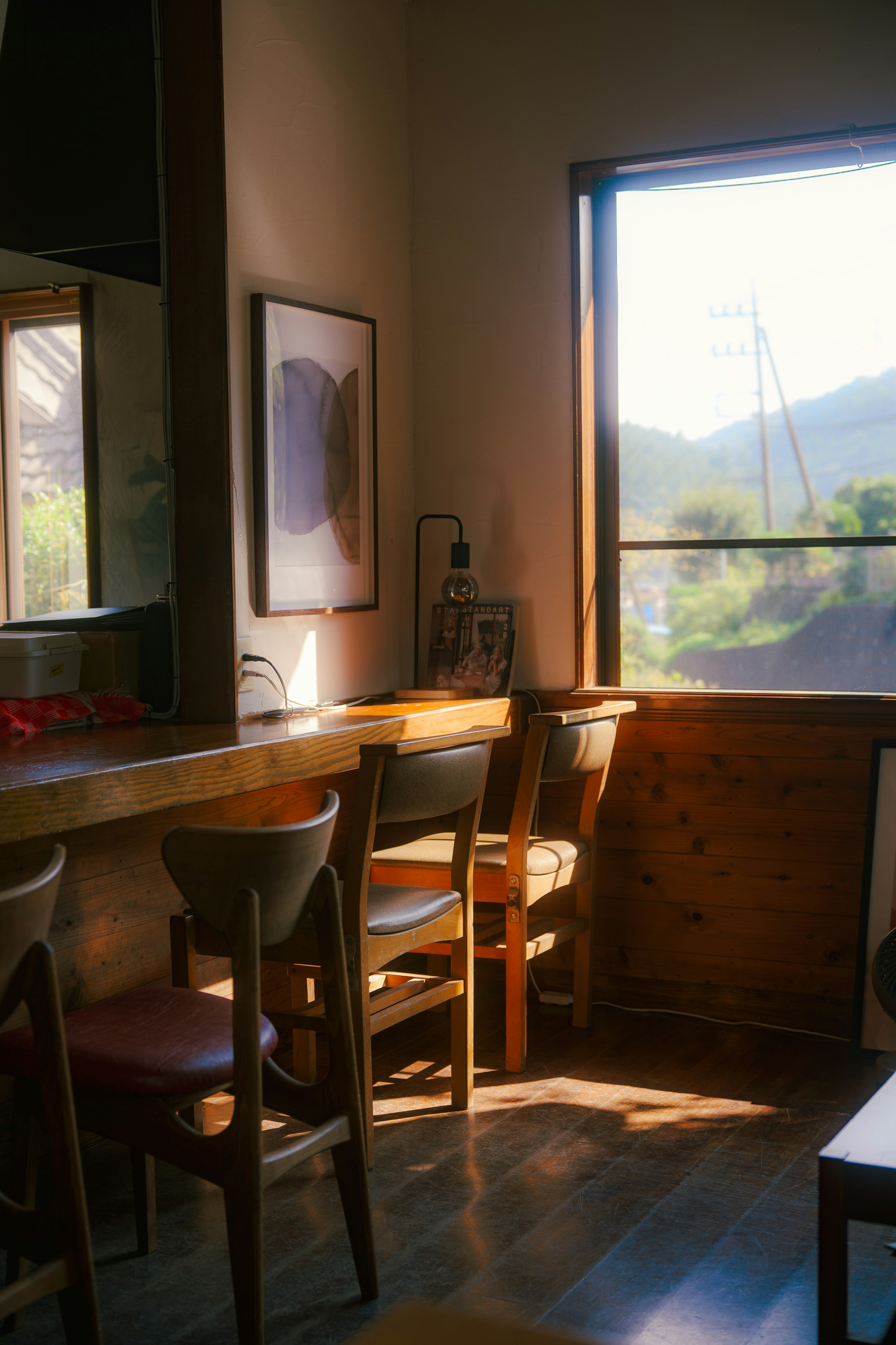 A cozy cafe corner with sunlight streaming through the window wooden counter and chairs visible