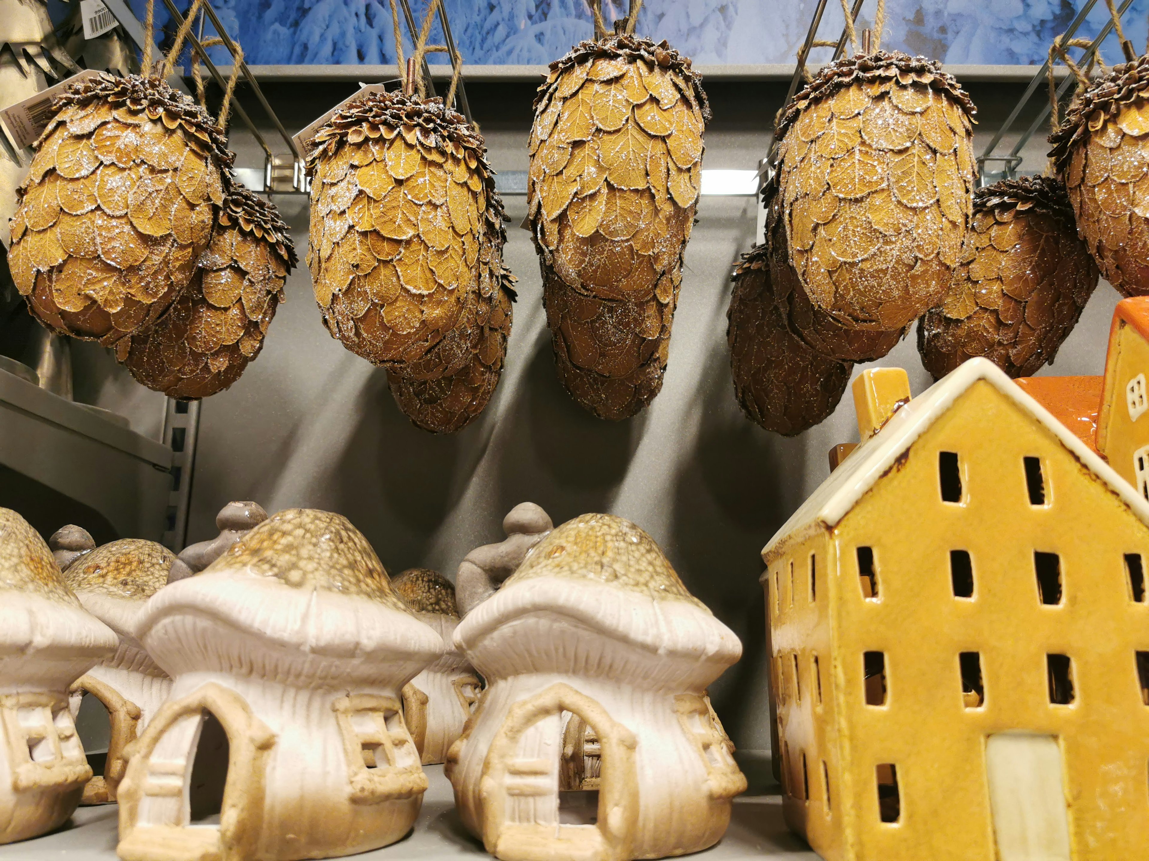 Rumah kayu dan dekorasi kerucut pinus yang digantung dipajang bersama