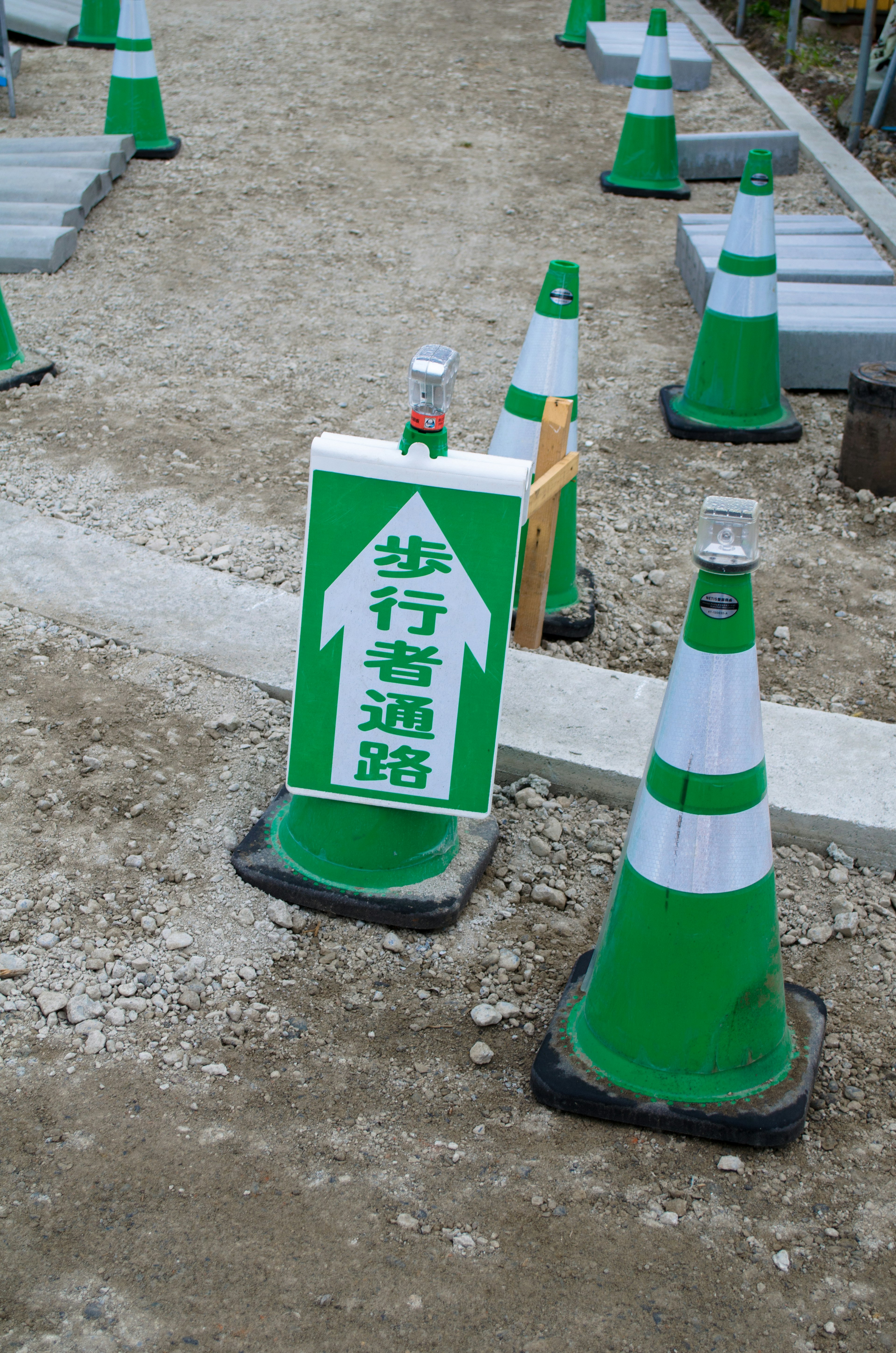 Señal verde de camino peatonal y conos en un sitio de construcción