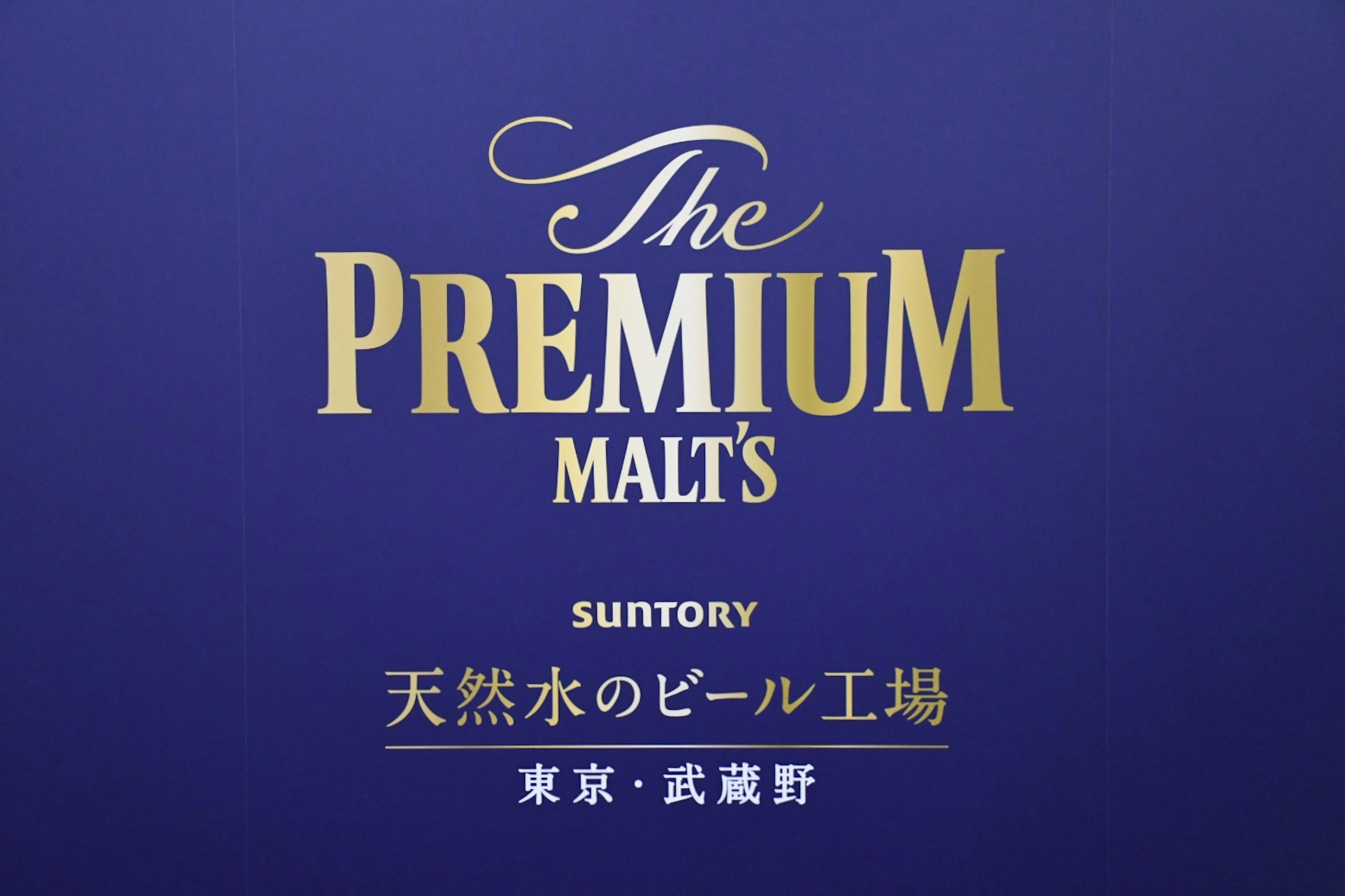 三得利的The Premium Malt's標誌設計，藍色背景和金色字母