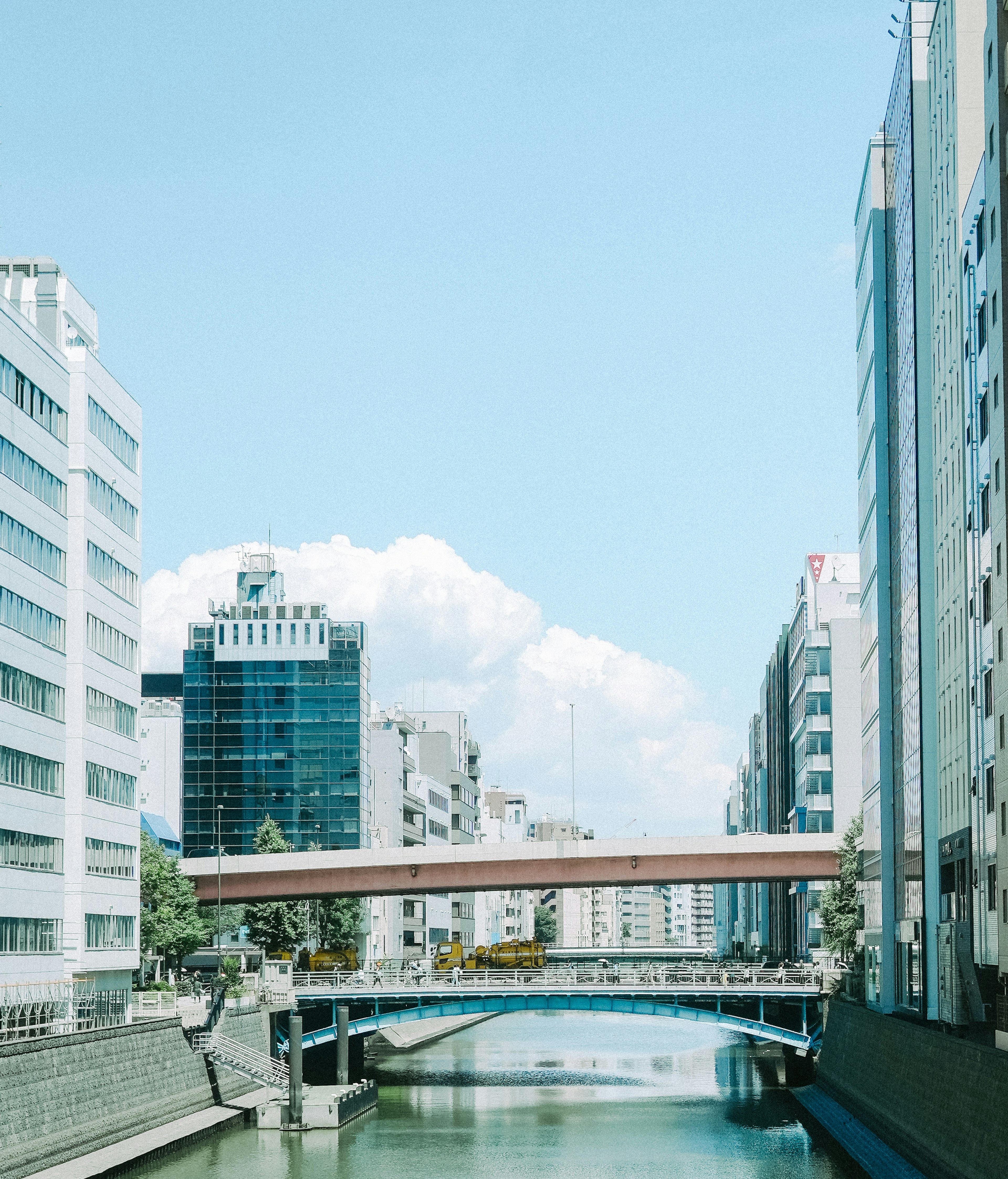 Escena urbana de un río con un puente bajo un cielo azul claro