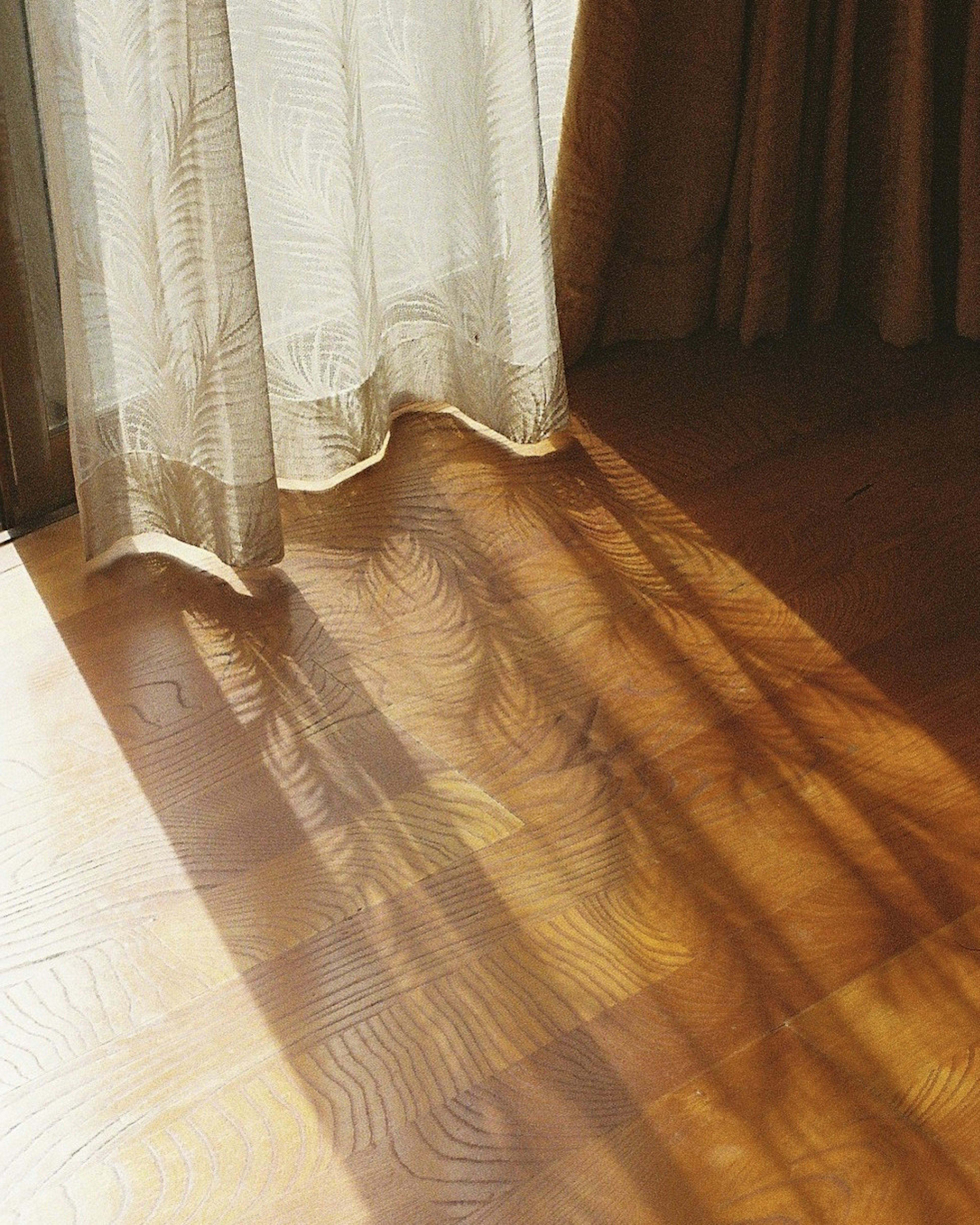 Escena de sombras de cortinas en el suelo Suelo de madera clara con luz solar