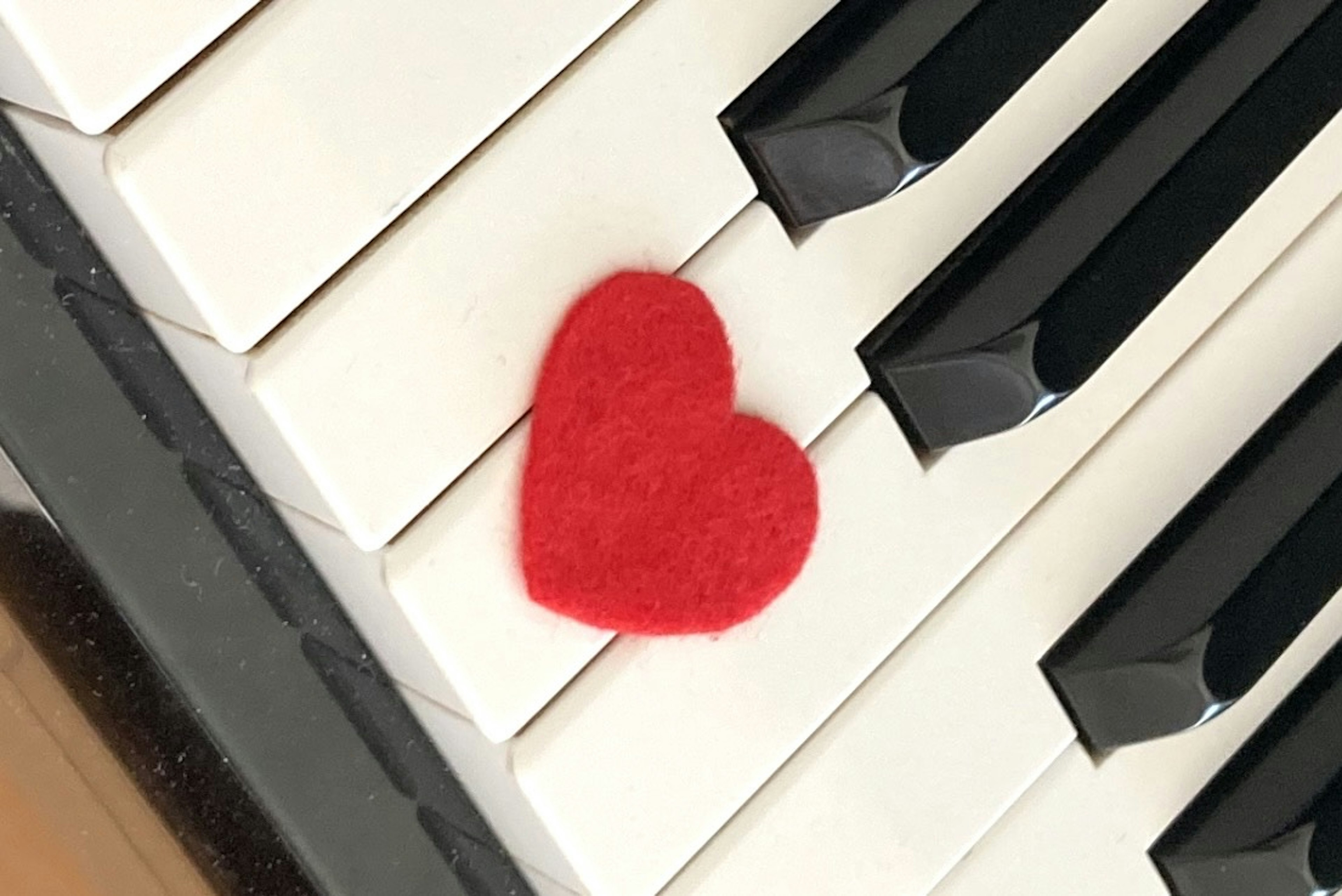 Hati felt merah di atas tuts piano