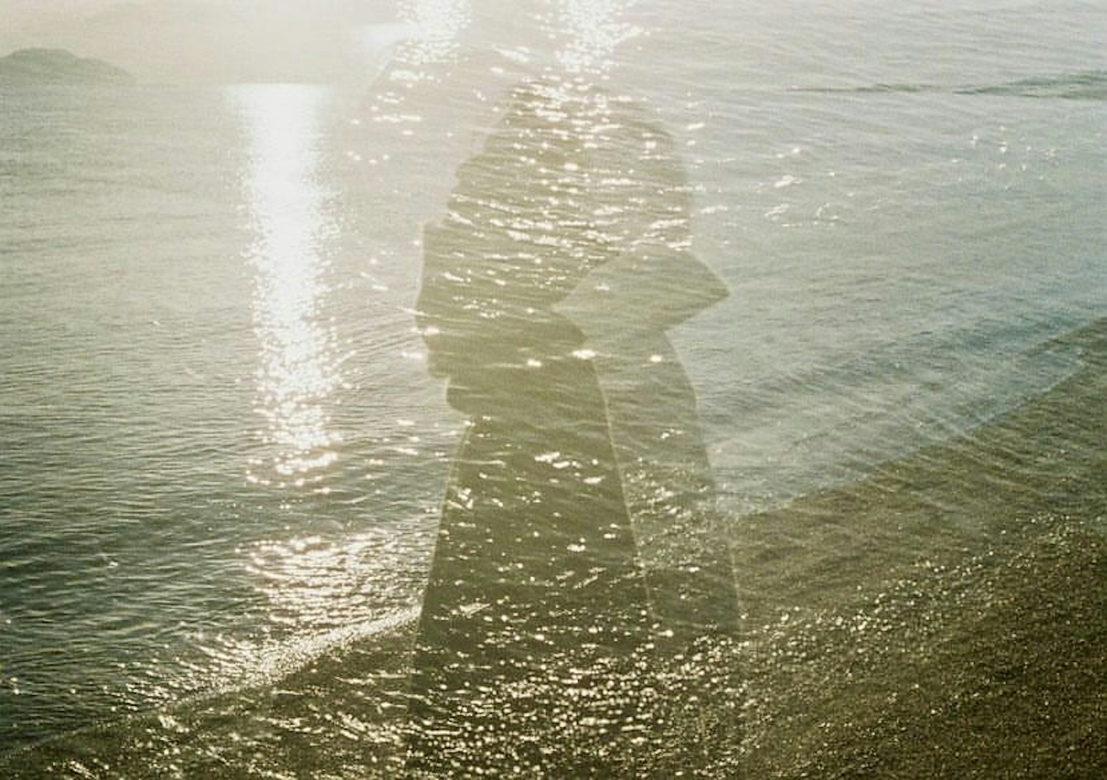 Silhouette of two people embracing reflected on the water surface at the beach