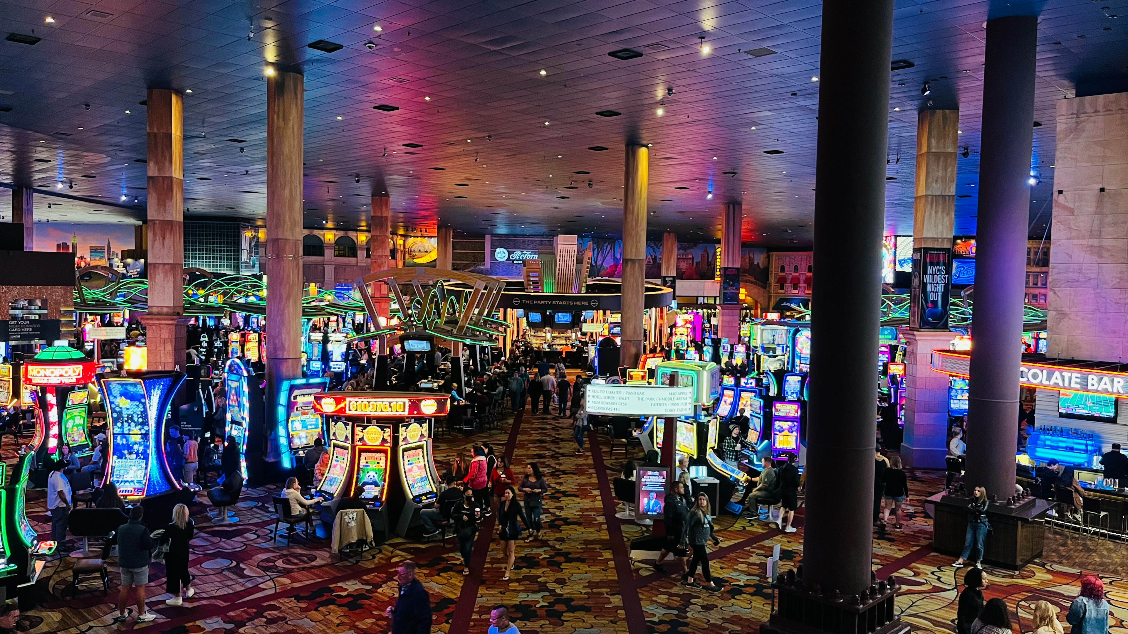 Interior view of a casino filled with slot machines and people