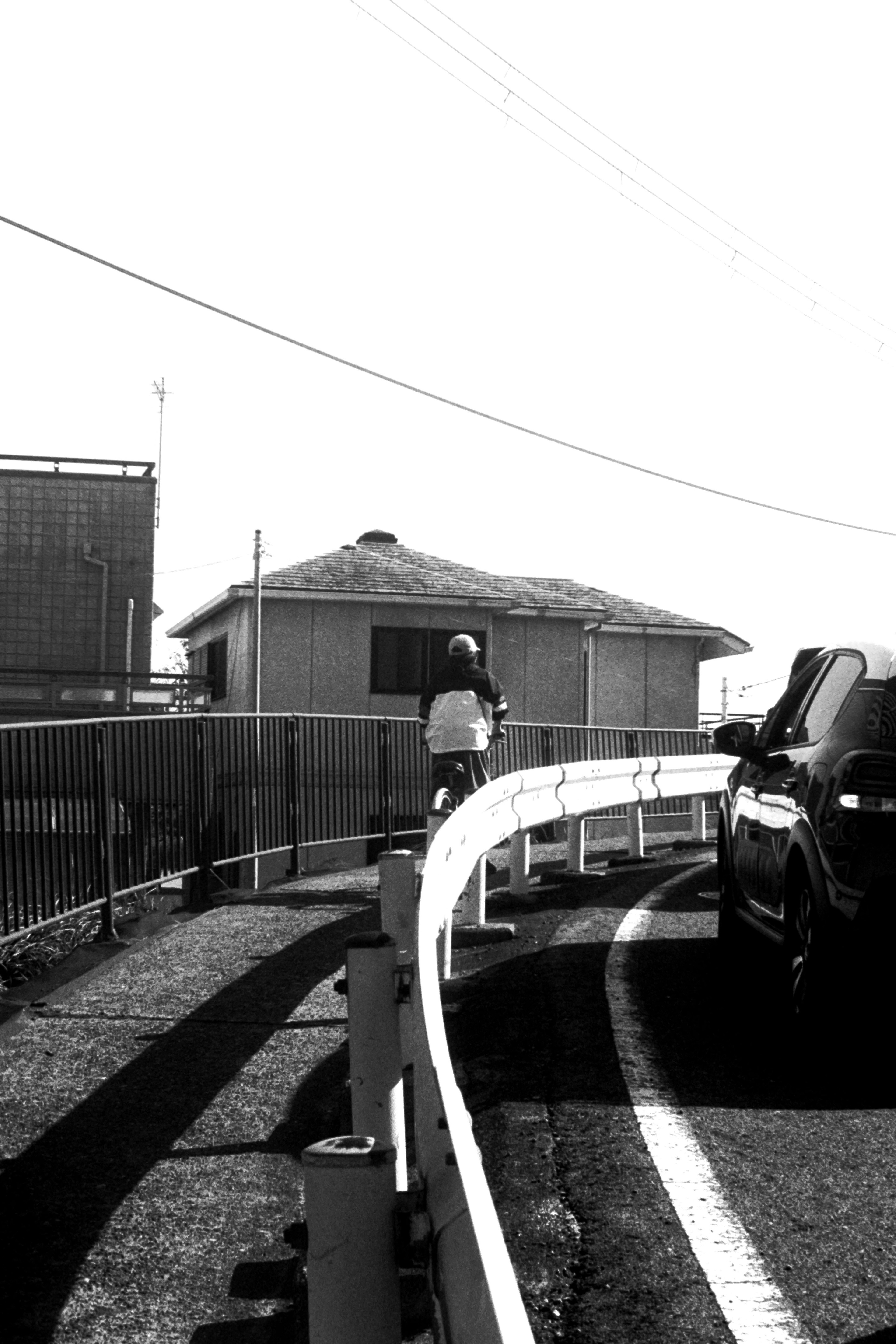 Escena en blanco y negro con una bicicleta en la carretera junto a un coche