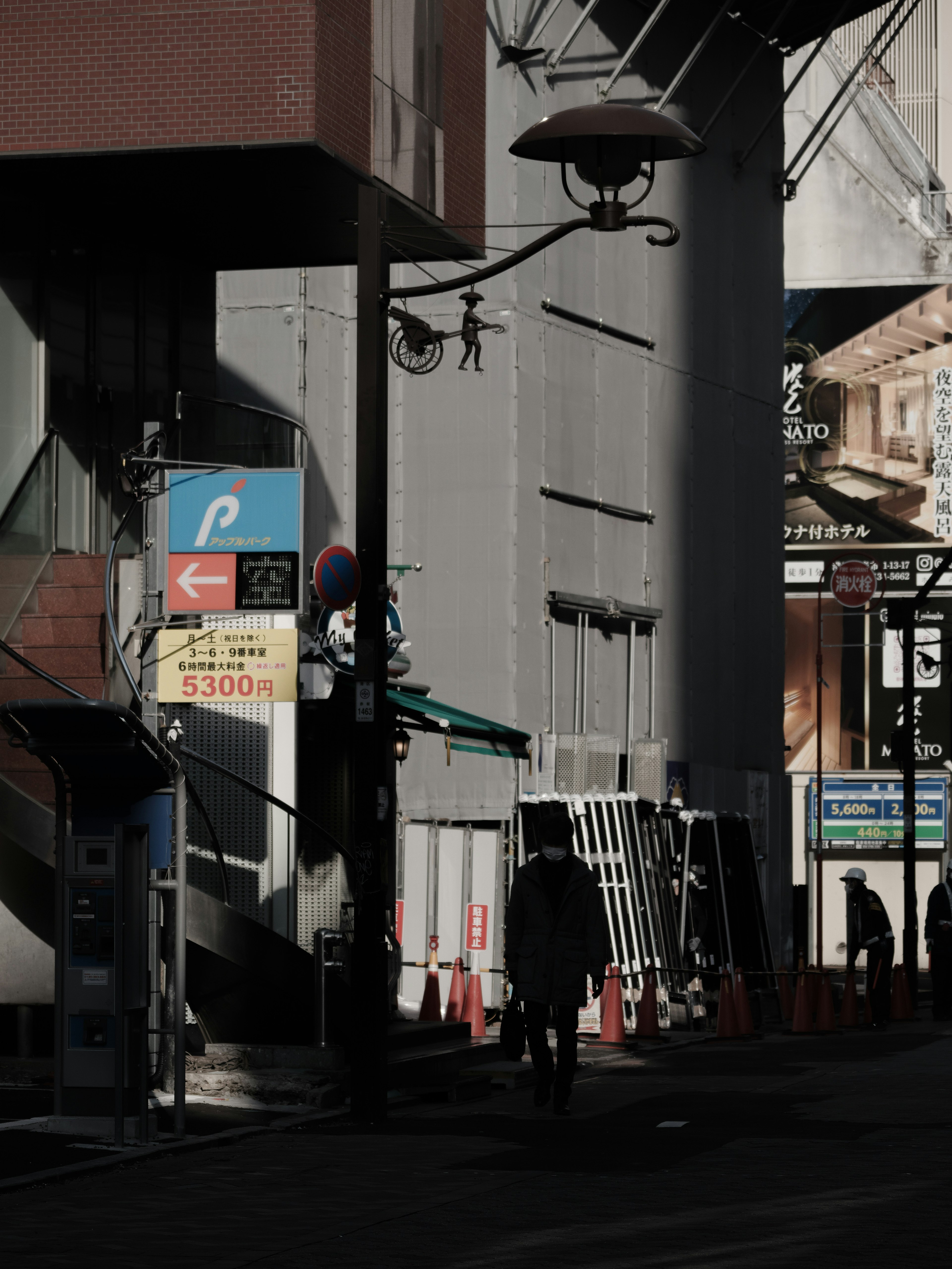 暗い街角に立つ人影と看板が見える都市の風景