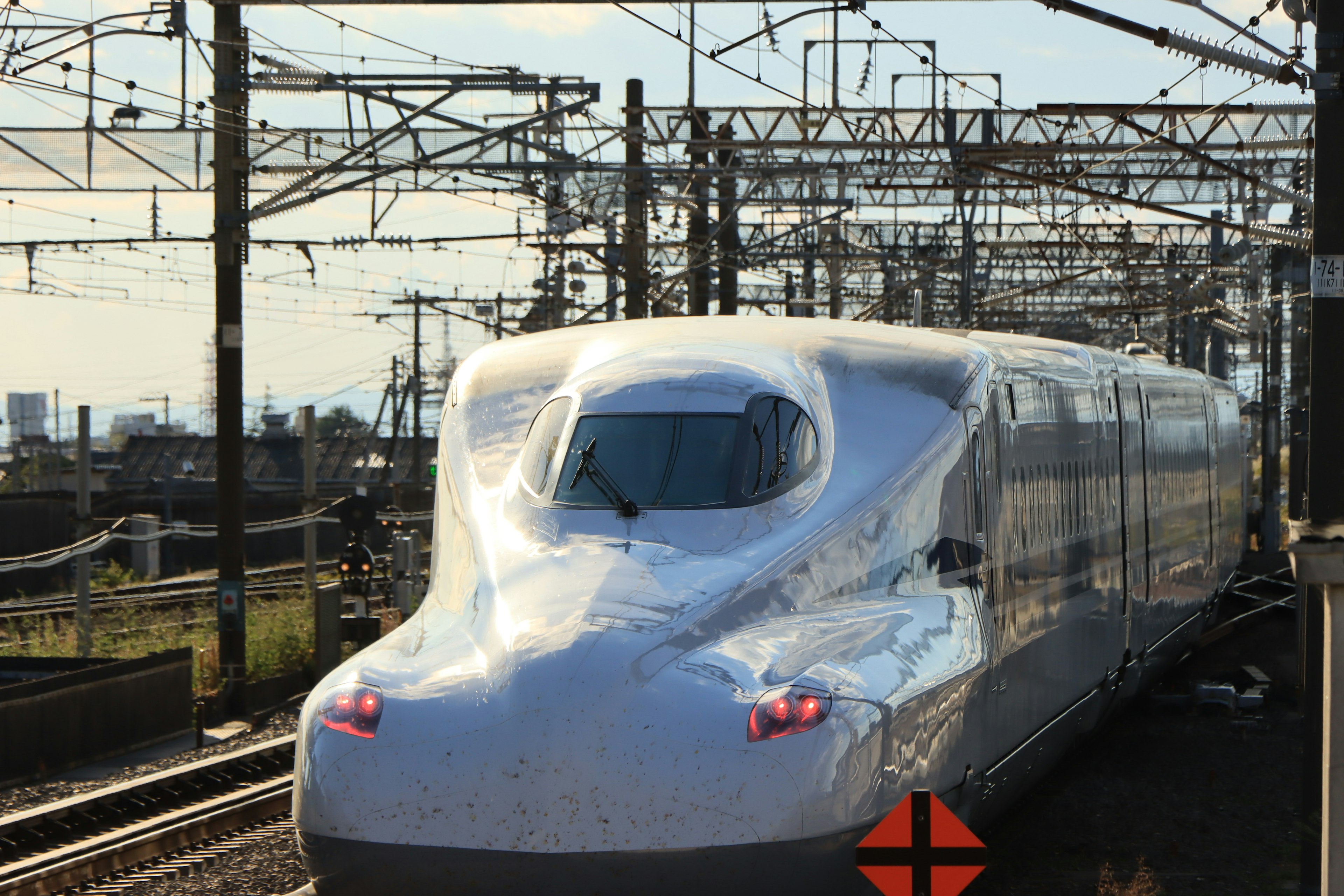 Shinkansen bullet train at a railway station with overhead lines