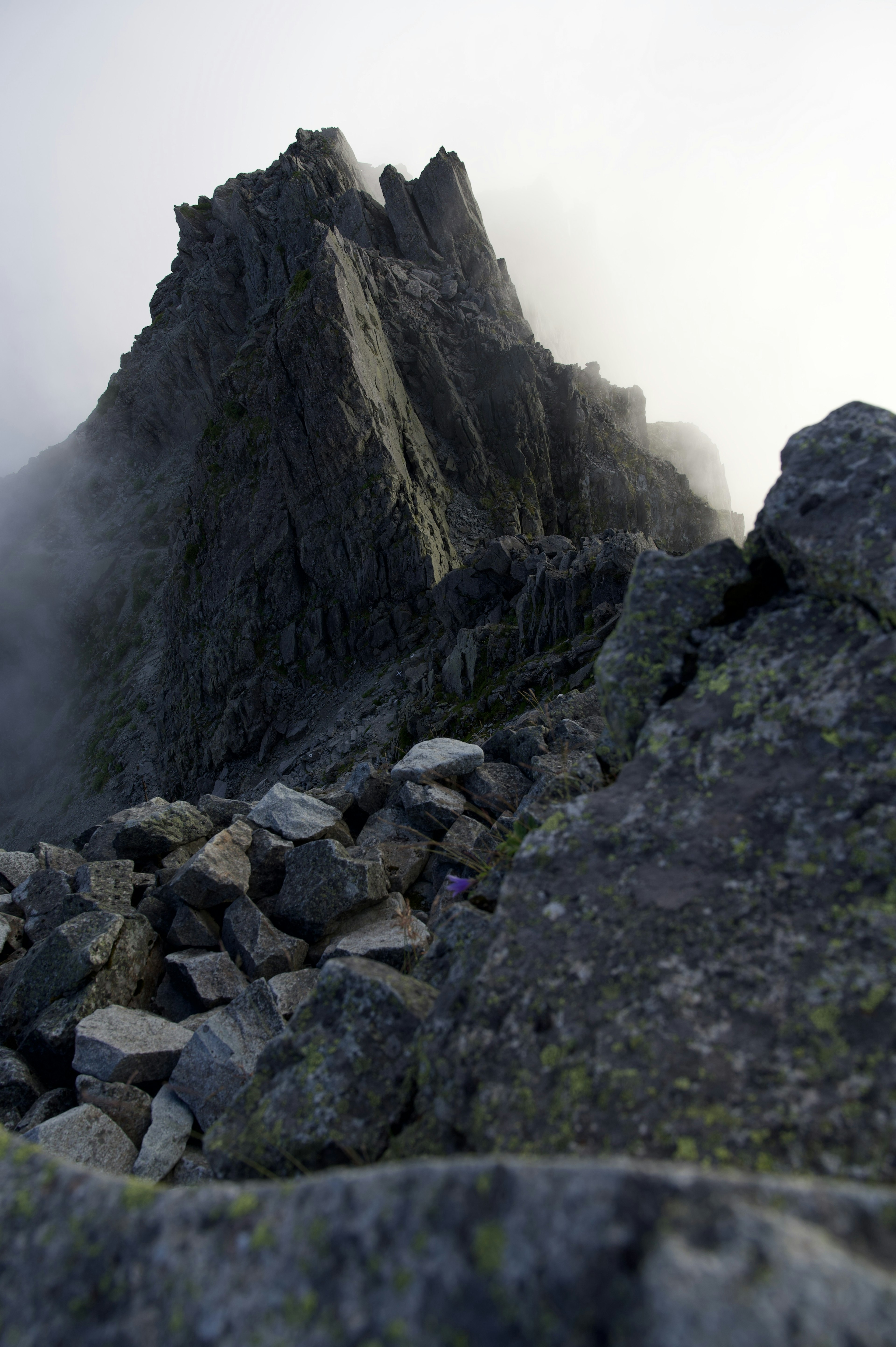 Sharp mountain peak shrouded in mist with rocky terrain