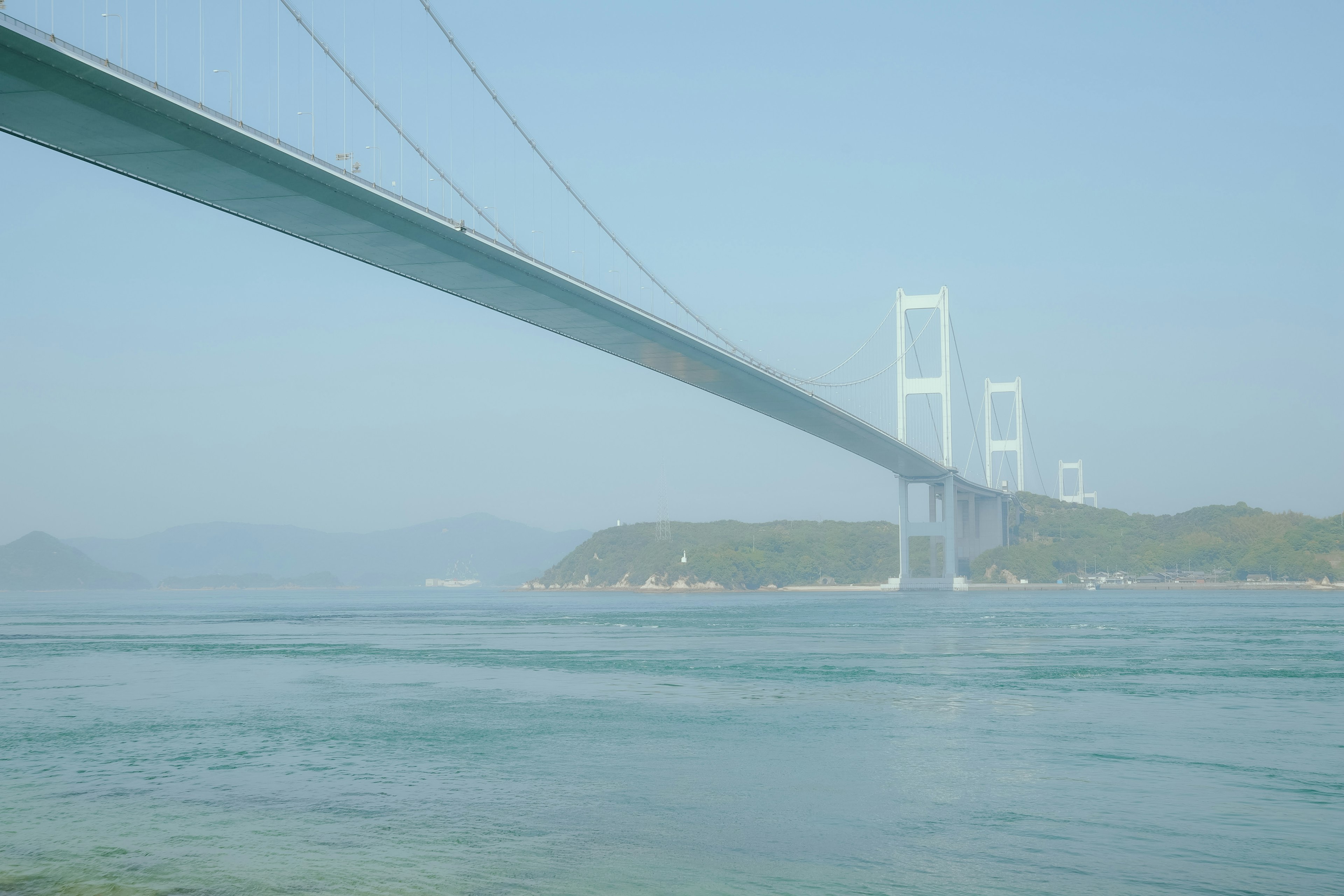 View of a bridge over blue water with a serene landscape in the background