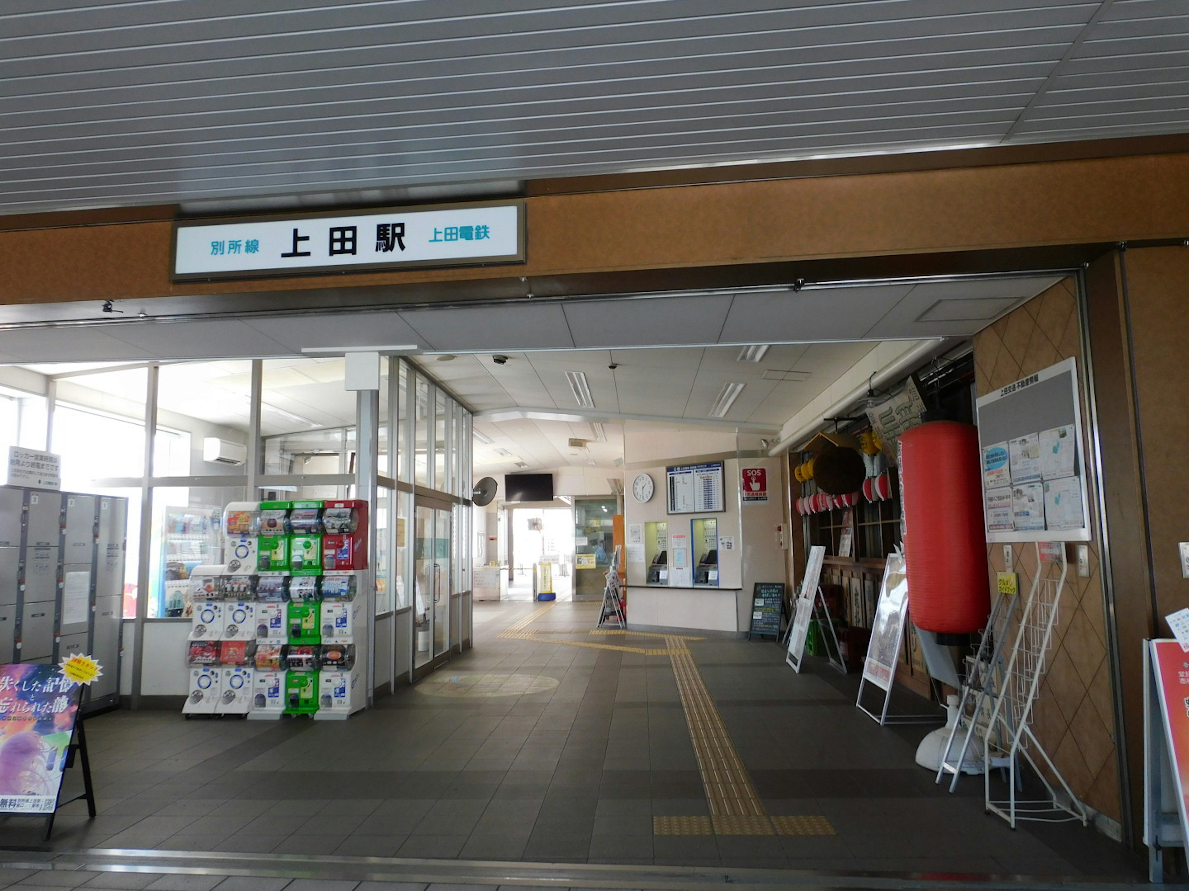 Interior view of Ueda Station featuring a waiting area with windows and information boards a prominent red punching bag