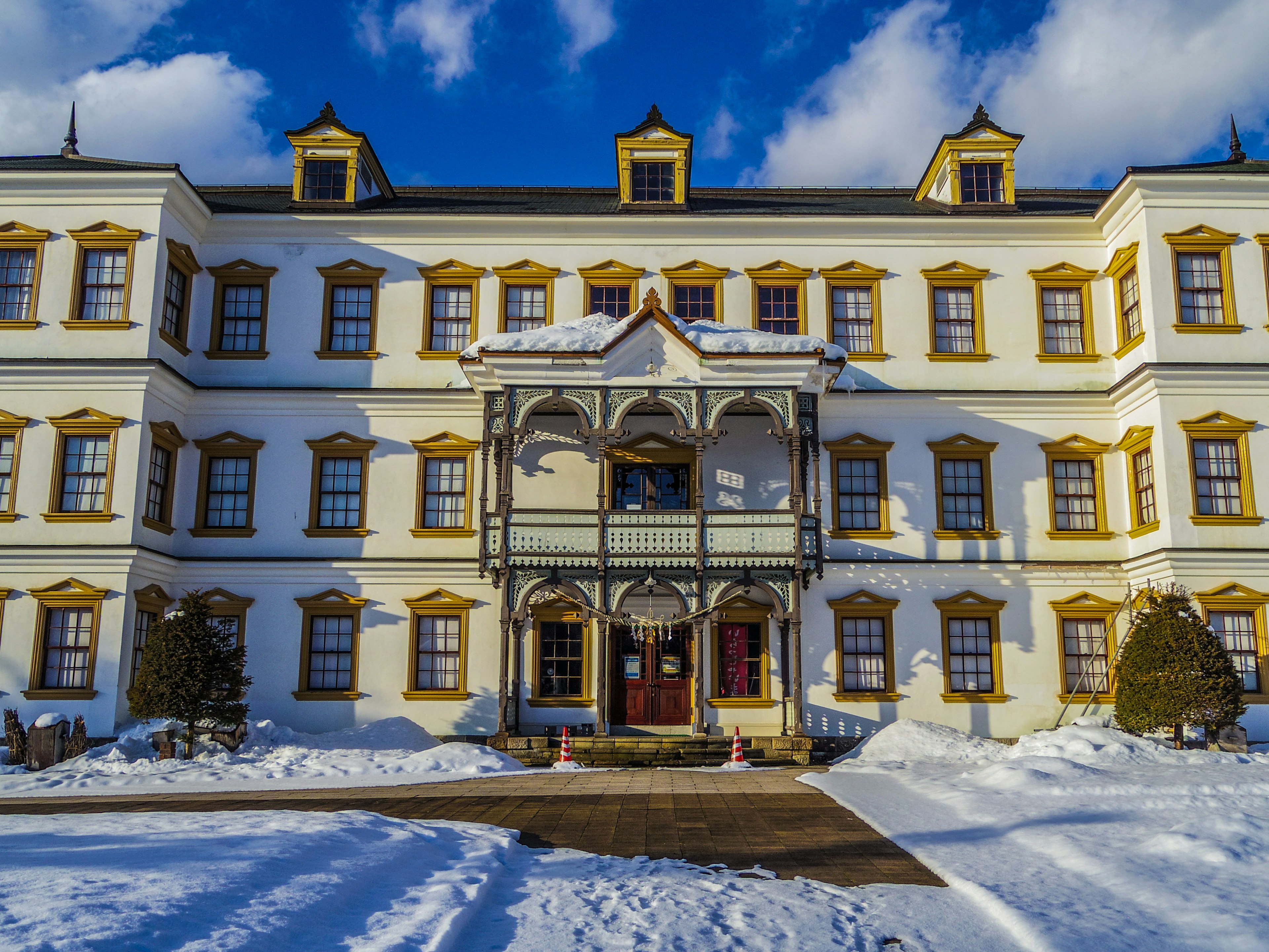 Schöne Fassade eines weißen Gebäudes mit gelben Akzenten umgeben von Schnee