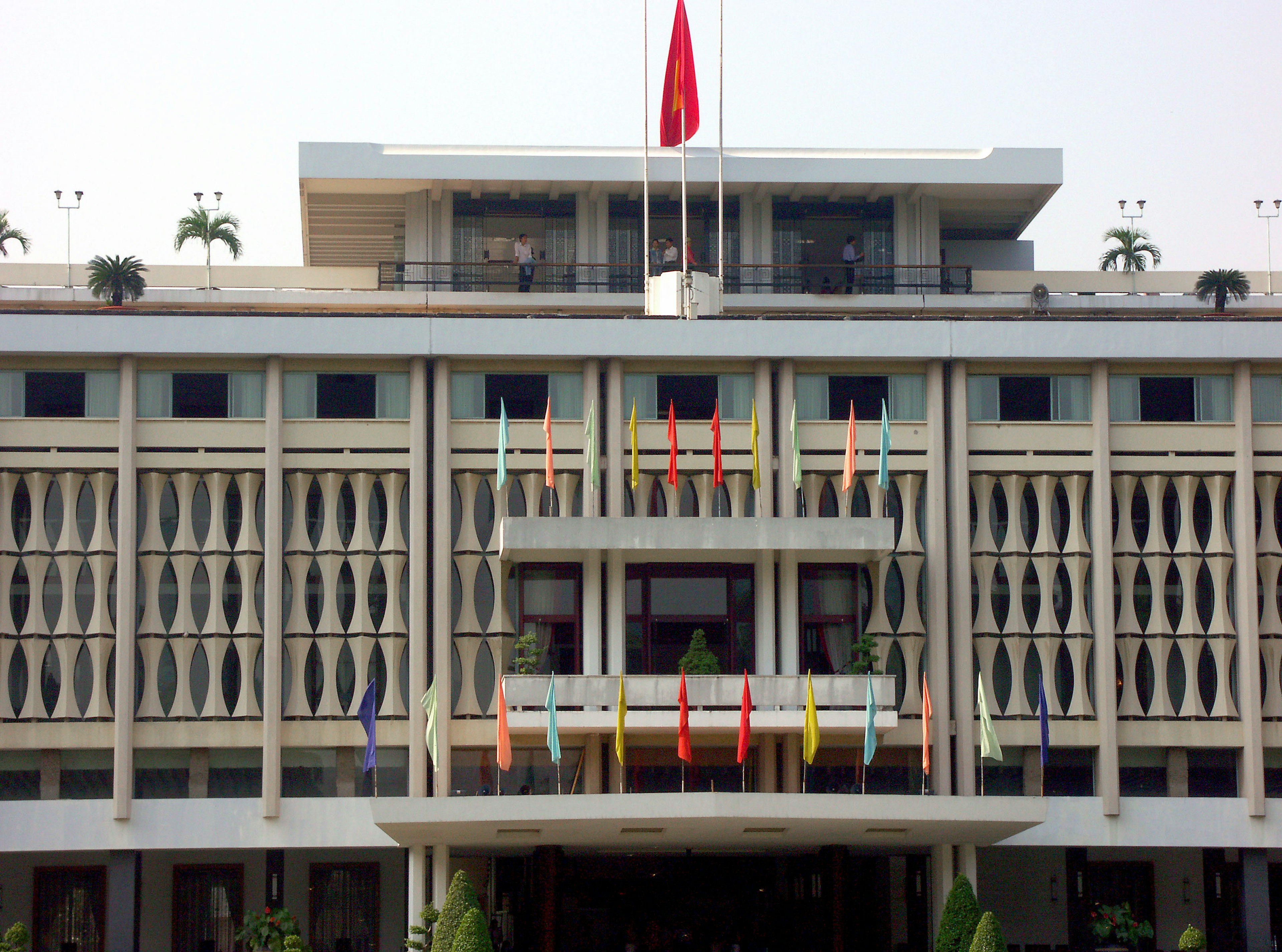 Fasad bangunan modern dengan bendera berwarna-warni dan bendera merah yang ditampilkan