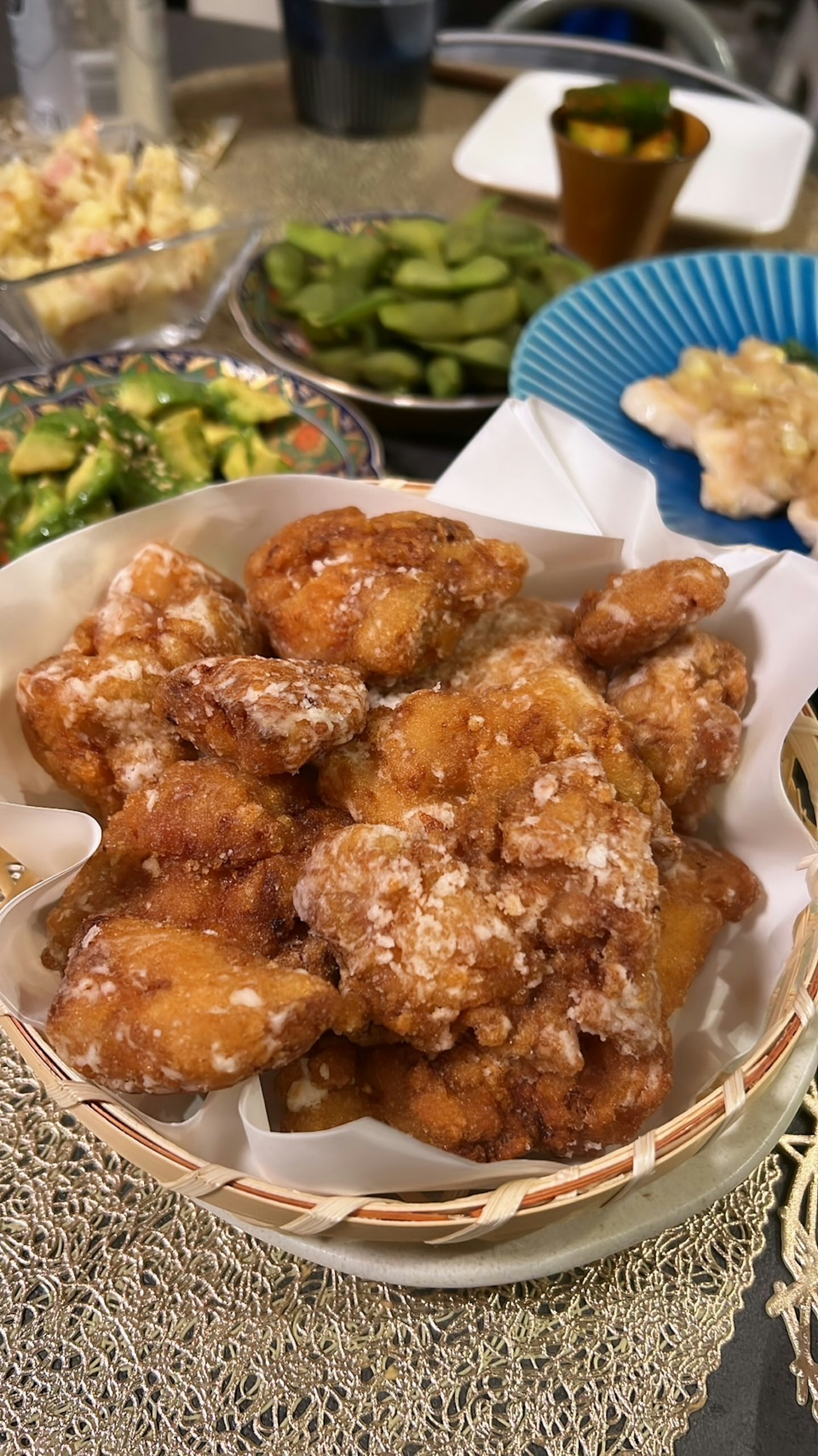 Una cesta de piezas de pollo frito servidas con varios acompañamientos al fondo