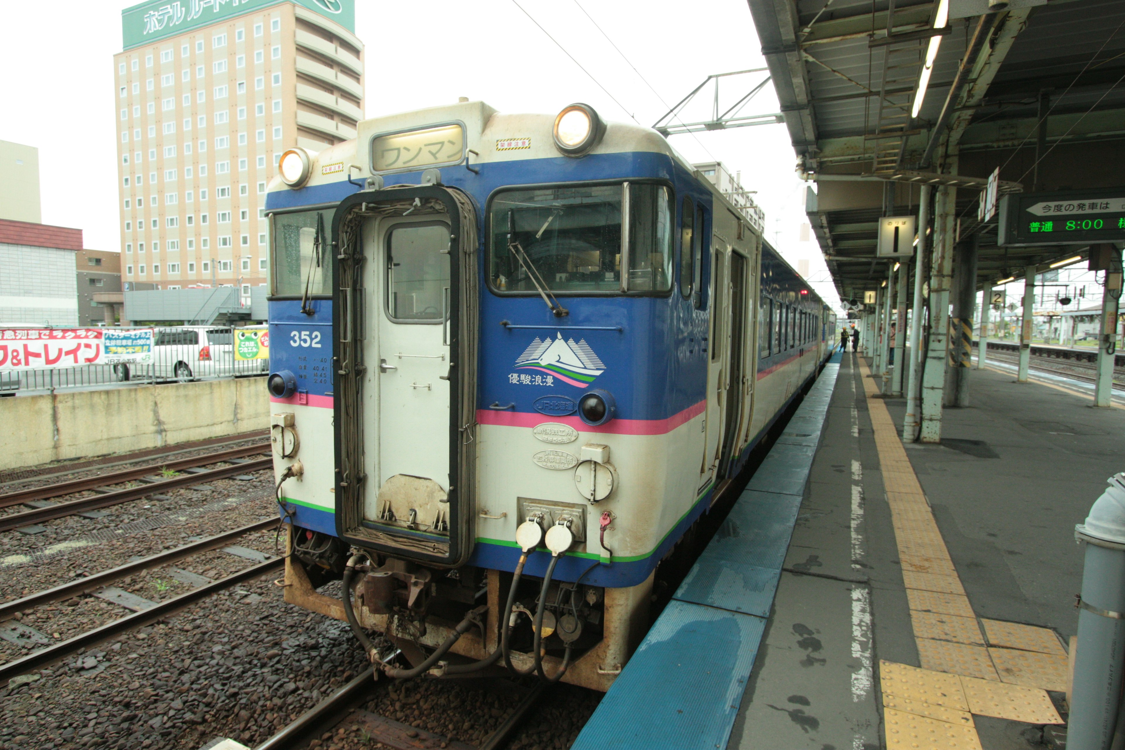 Tren azul y blanco en una estación con edificios circundantes