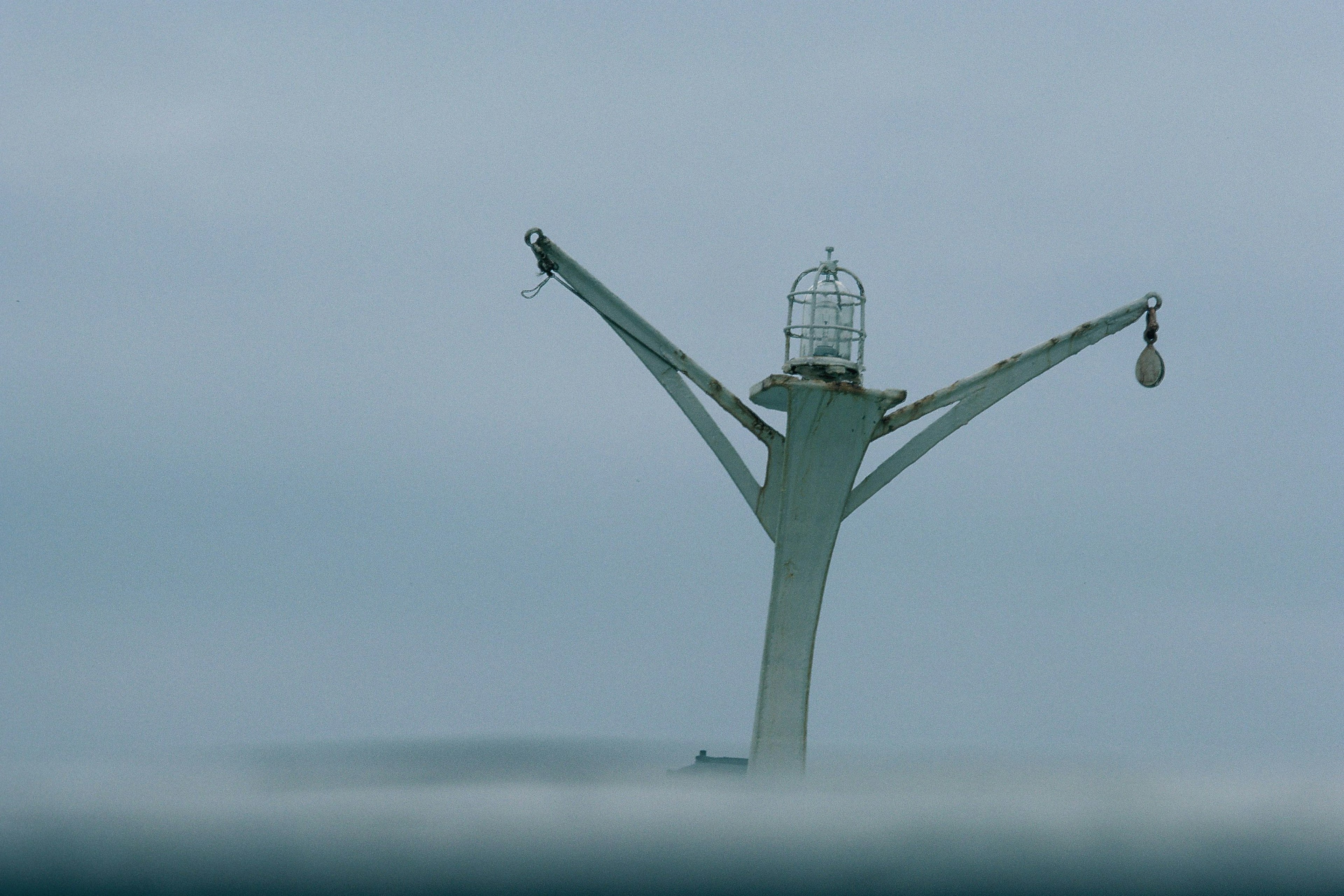 Una estructura similar a un faro se eleva sobre el océano envuelto en niebla