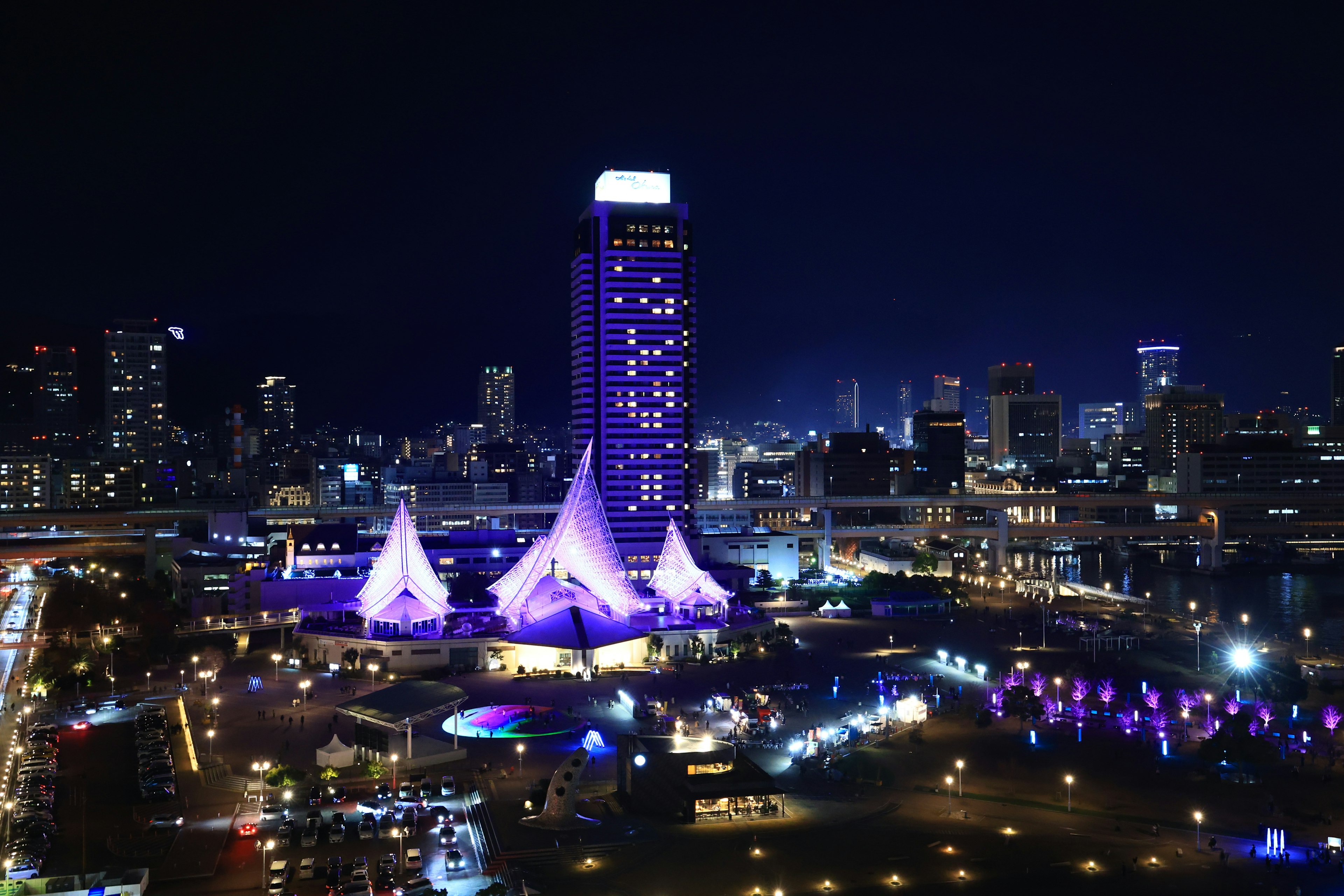 Paysage urbain nocturne avec des tentes violettes et un grand bâtiment